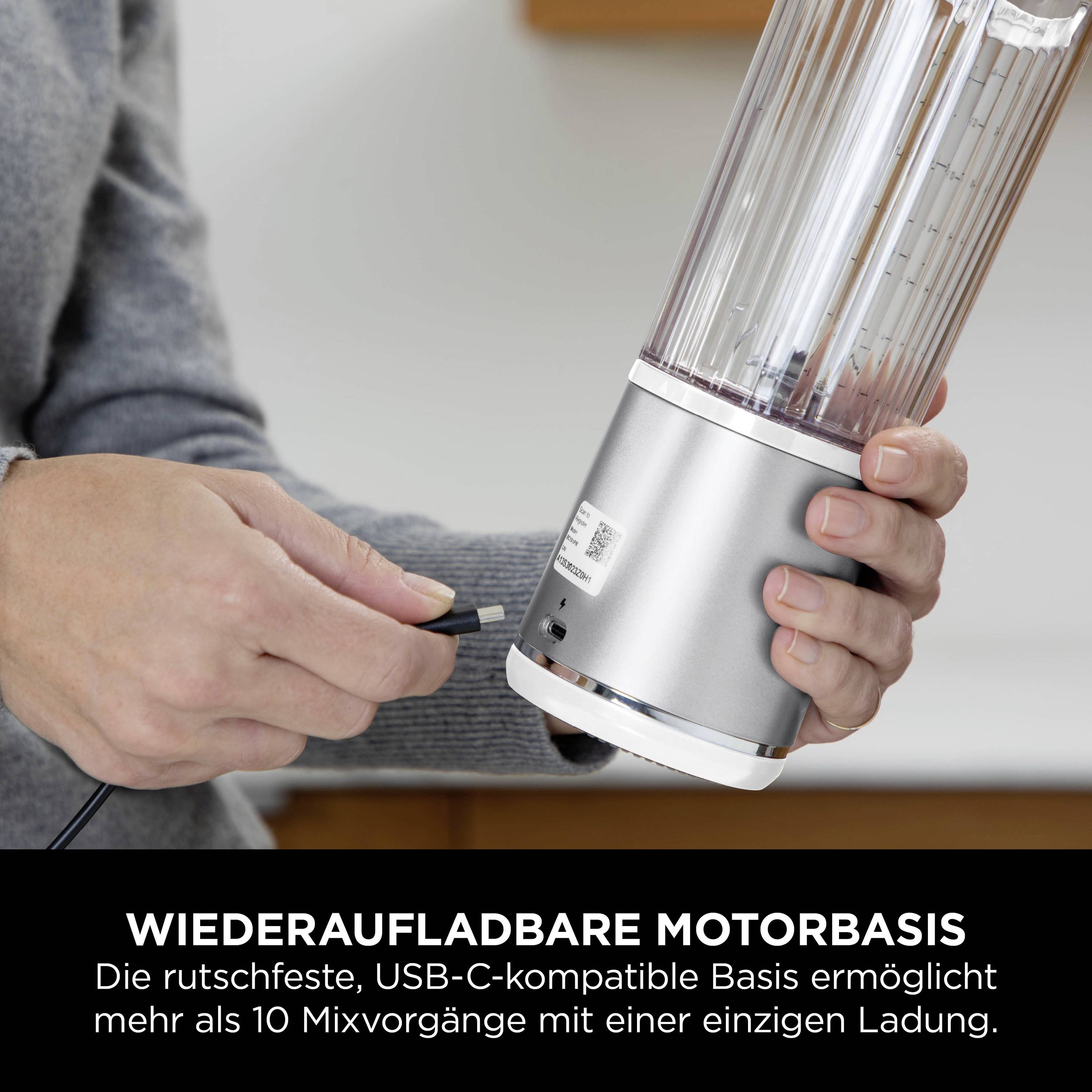 Eine Person hält den abnehmbaren Teil eines wiederaufladbaren Mixers, während sie ein USB-C-Kabel zum Aufladen einsteckt. Text: 'Wiederaufladbare Motorbasis'.