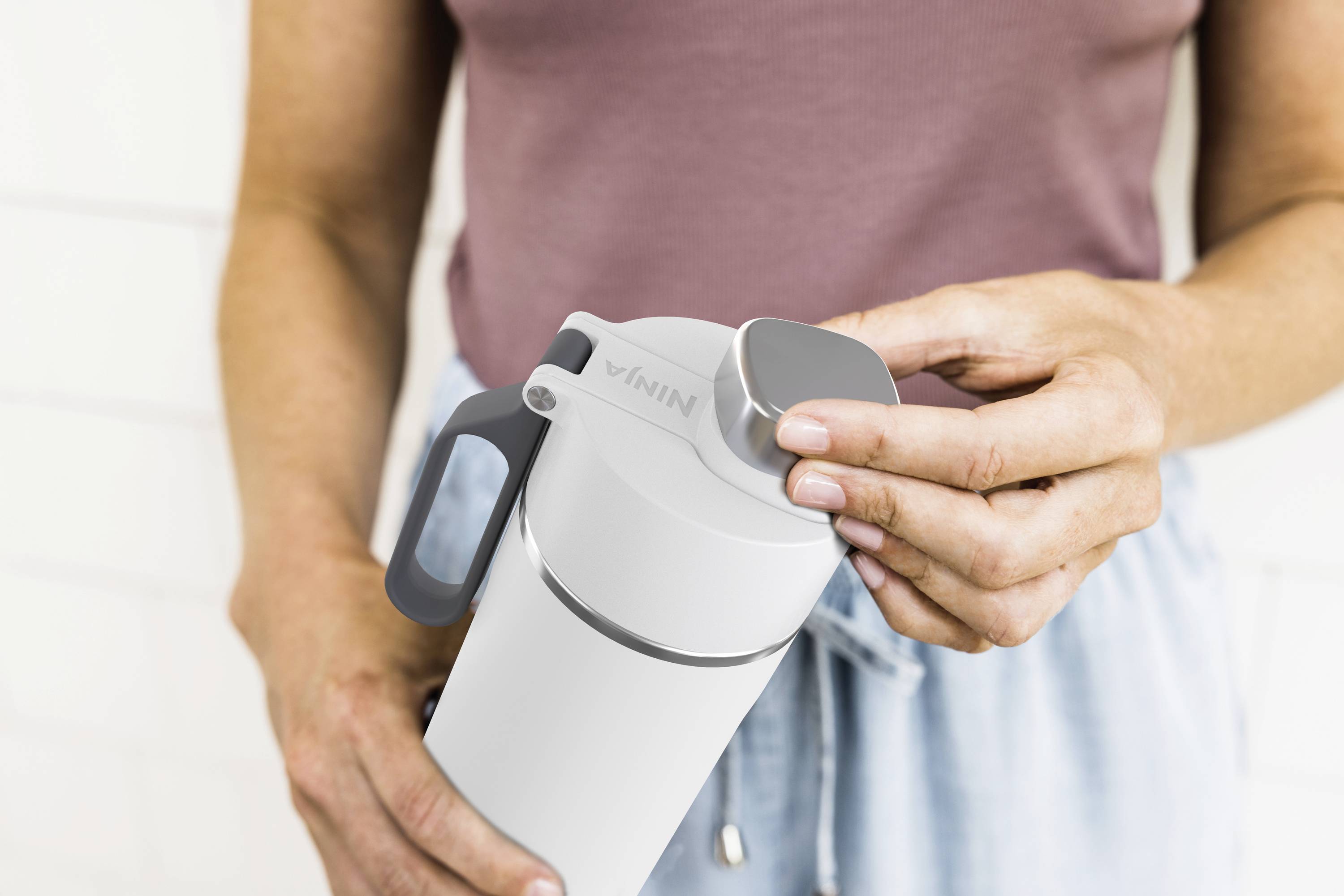 Eine Person hält eine weiße Trinkflasche und öffnet den Verschluss.