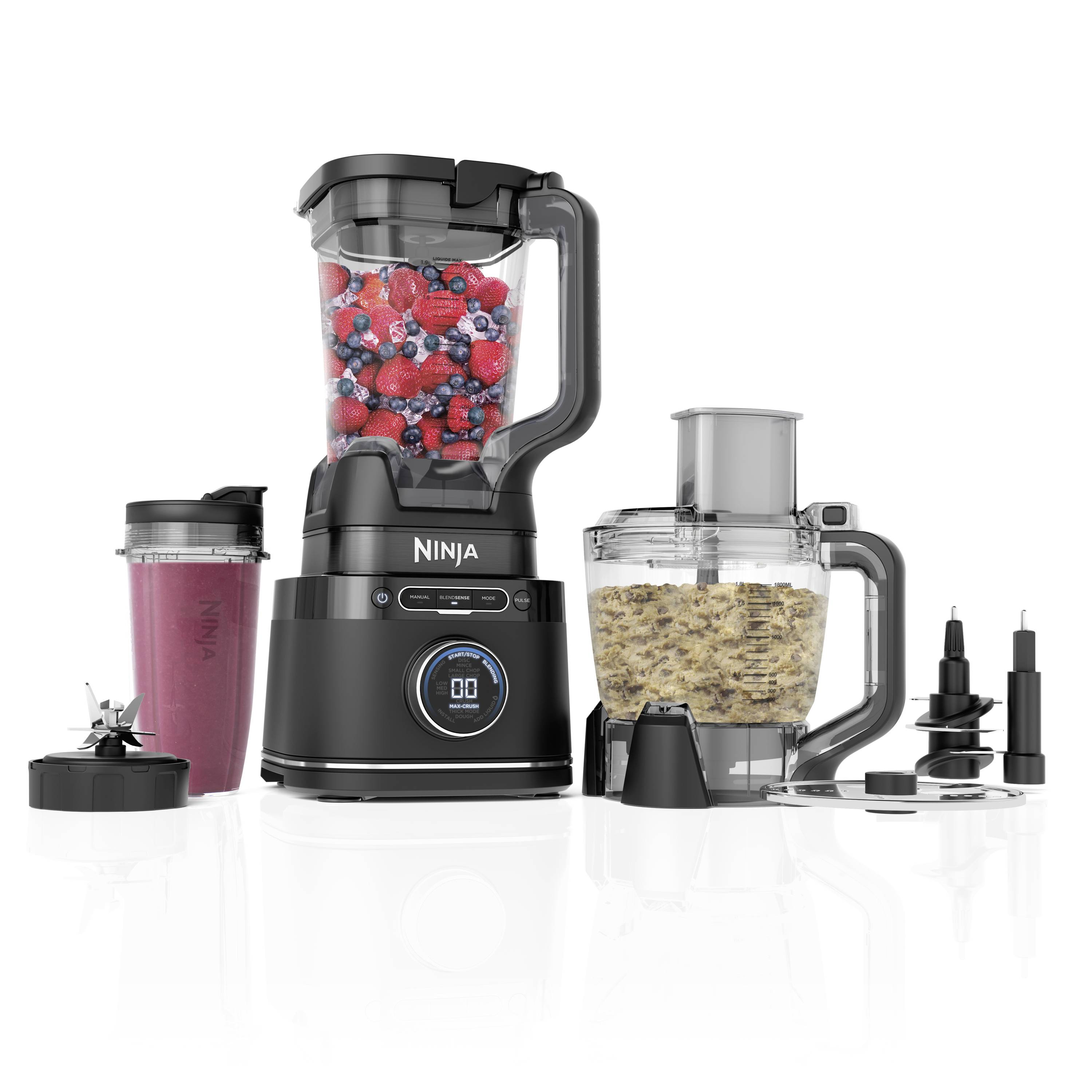 Ein Mixer-Set bestehend aus Mixer, Behälter mit roten Beeren, eine Schüssel mit gemahlenem Getreide und drei verschiedenen Klingenaufsätzen.