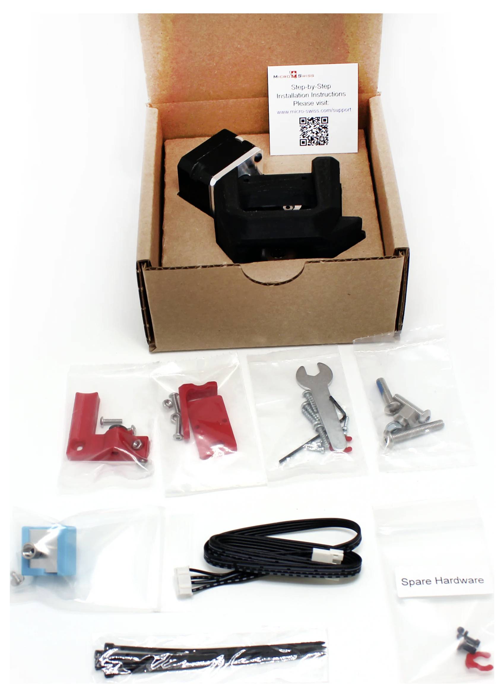 Offene Pappschachtel mit einem schwarzen Gerät und einer Anleitung, sowie darunter angeordnete Hardware-Beutel, Kabel, Ersatzteil und Werkzeuge.