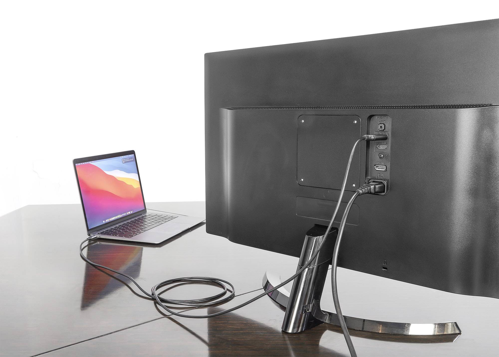 Ein Laptop ist mit einem großen Monitor verbunden, beide auf einem Holztisch. Der Bildschirm zeigt nicht, was dargestellt wird.