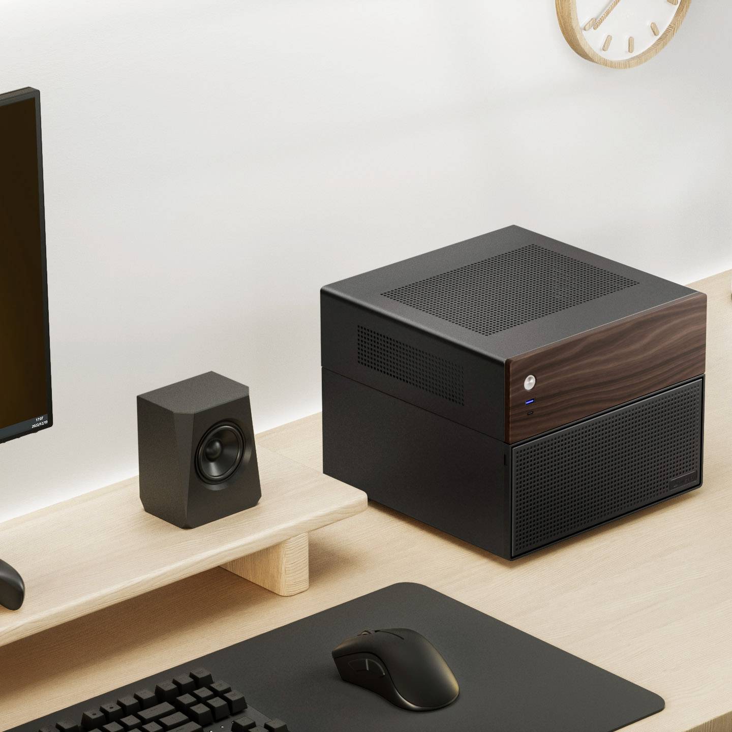 Ein moderner Computerarbeitsplatz mit einem kompakten Desktop-PC, Monitor, Lautsprecher, Maus und Uhr an der Wand.