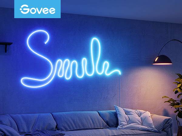 Neoninstallation mit dem Schriftzug 'Smile' in Blau an einer Wand über einem Sofa, beleuchtet neben einer modernen Lampe.