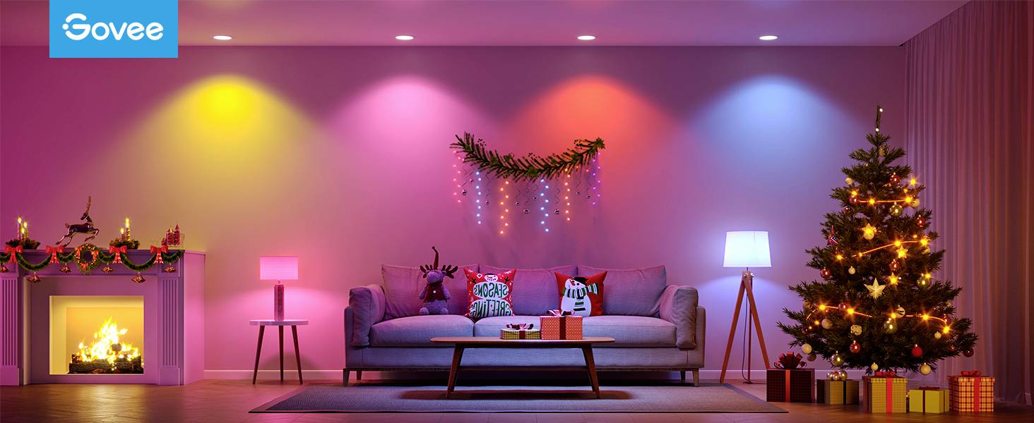 Farbig beleuchtetes Wohnzimmer mit Weihnachtsdekoration, Sofa mit Kissen, Tisch mit Geschenken, geschmücktem Weihnachtsbaum und Kaminfeuer.