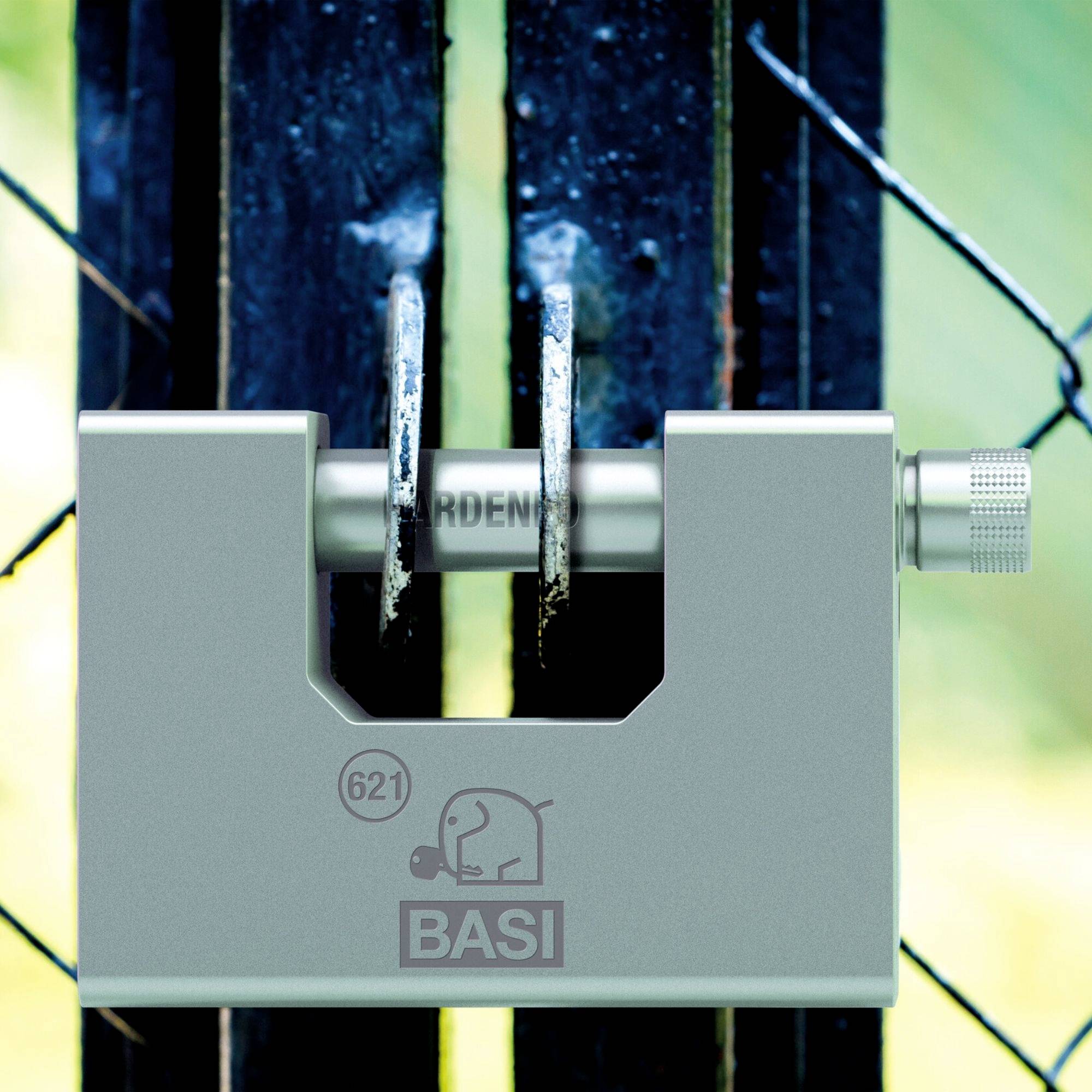 Ein massives Vorhängeschloss mit der Aufschrift 'BASI', verschließt ein Gittertor, symbolisiert Sicherheit und Schutz.