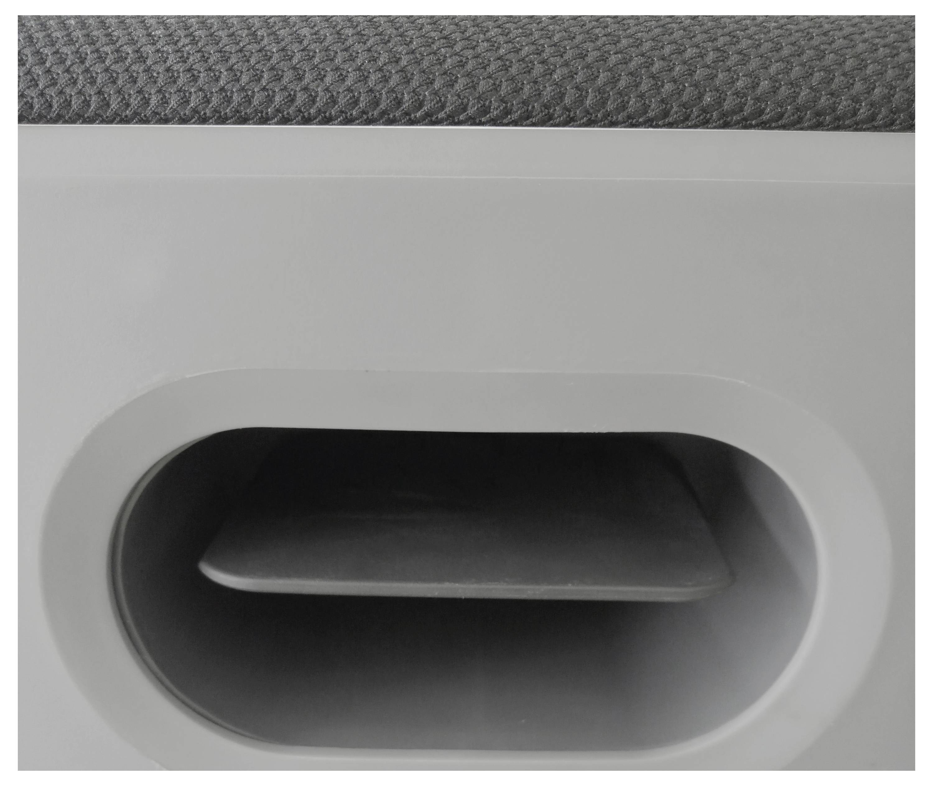 Ein Ausschnitt eines grauen Möbelstücks mit einem ovalen Griff oder Öffnung, zeigt Textur und Form.