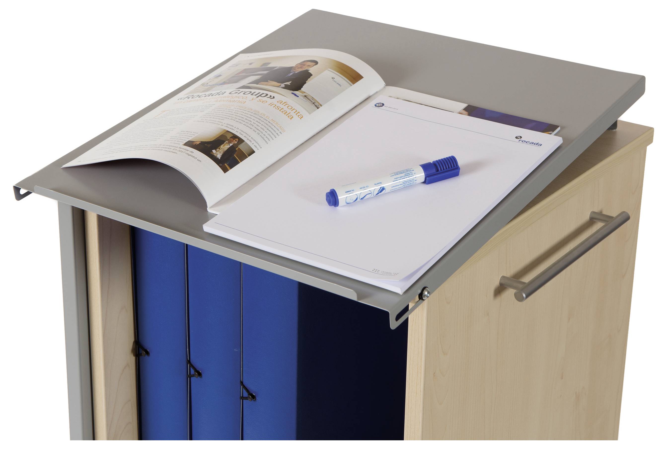 Zeitung und Schreibutensilien auf einem Aktenschrank mit offenen Aktenordnern.