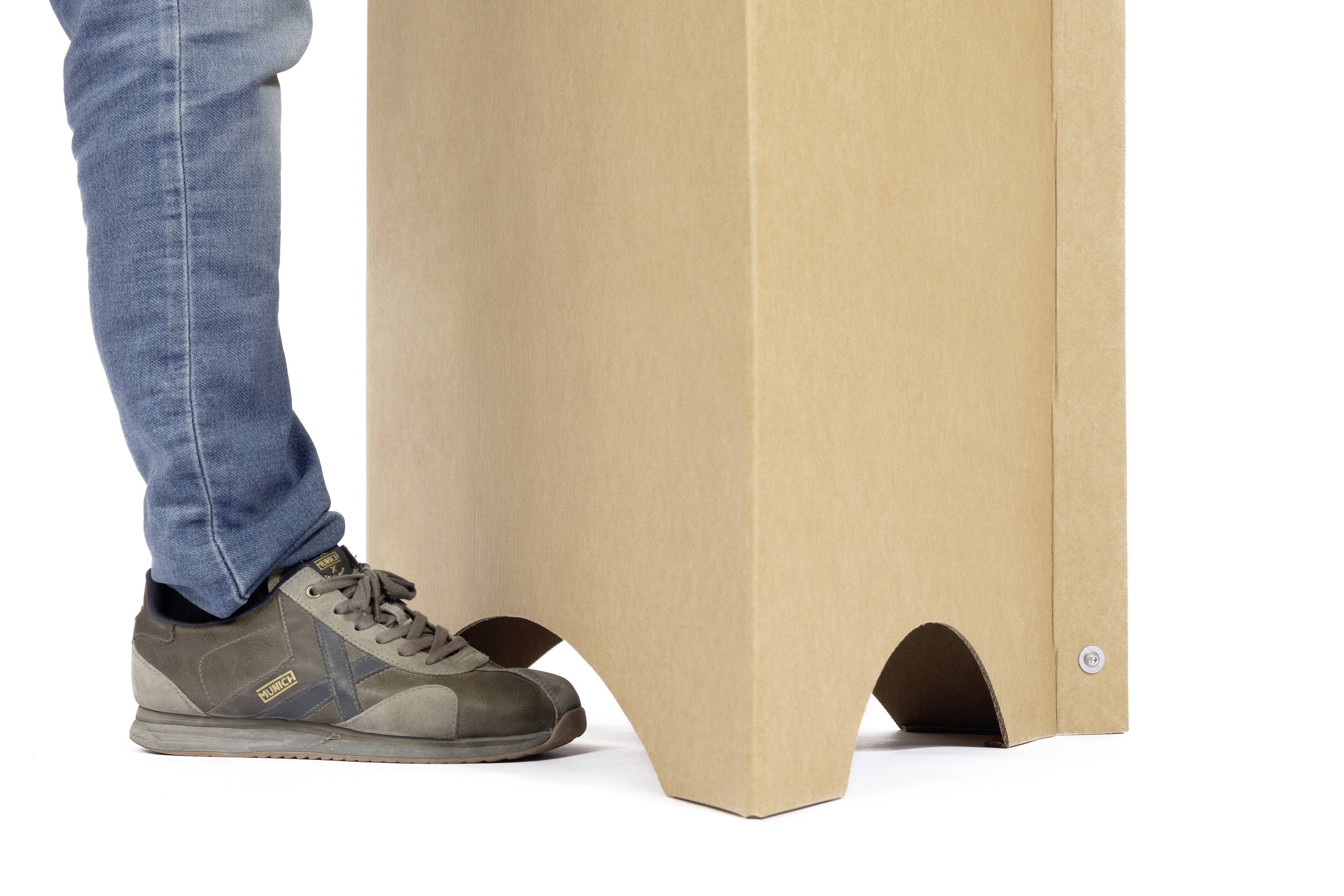 Ein Bein in Jeans und Turnschuh drückt einen Kartonständer.