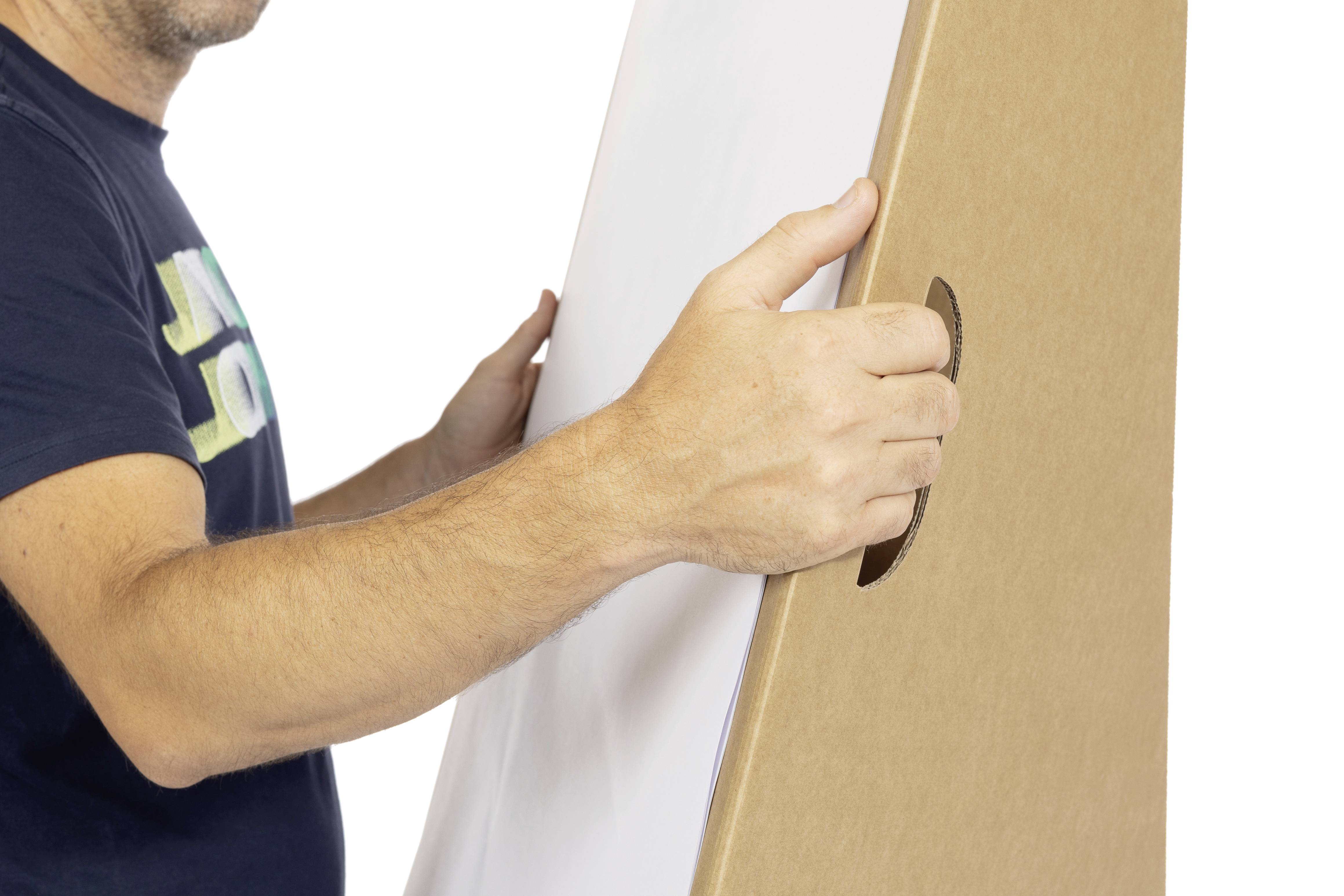 Eine Person hält einen großen, braunen Karton mit einer weißen Oberfläche. Die Hände greifen seitlich durch Grifföffnungen.