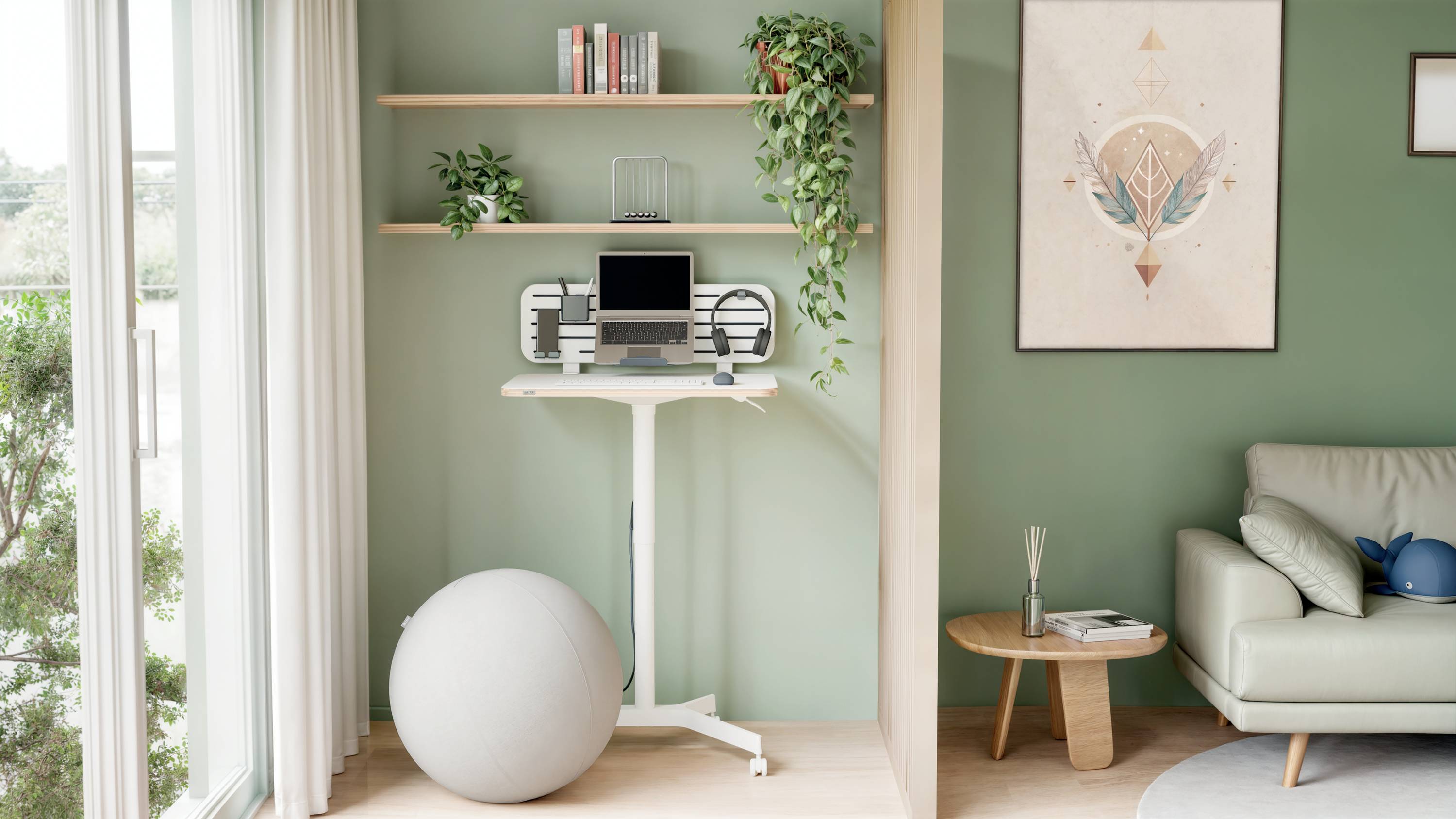 Stehpult mit Laptop und Monitor im minimalistischen Zimmer mit grünen Wänden, Pflanzen und Sitzball, neben einem Fenster mit Tageslicht.
