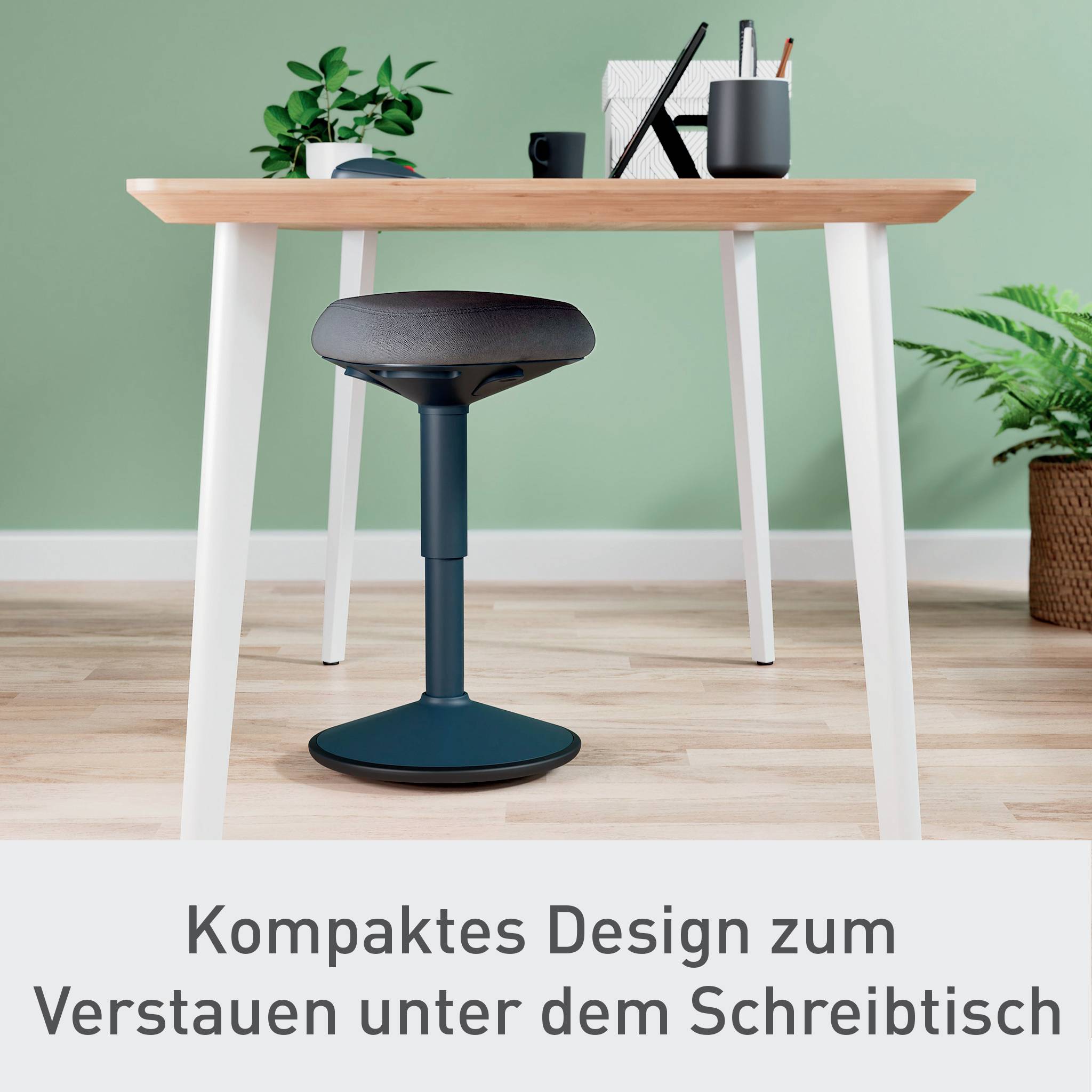 Ein moderner Schreibtisch mit einem kleinen Hocker darunter, umgeben von Pflanzen und Büromaterial. Text: 'Kompaktes Design für Verstauen unter dem Schreibtisch'.