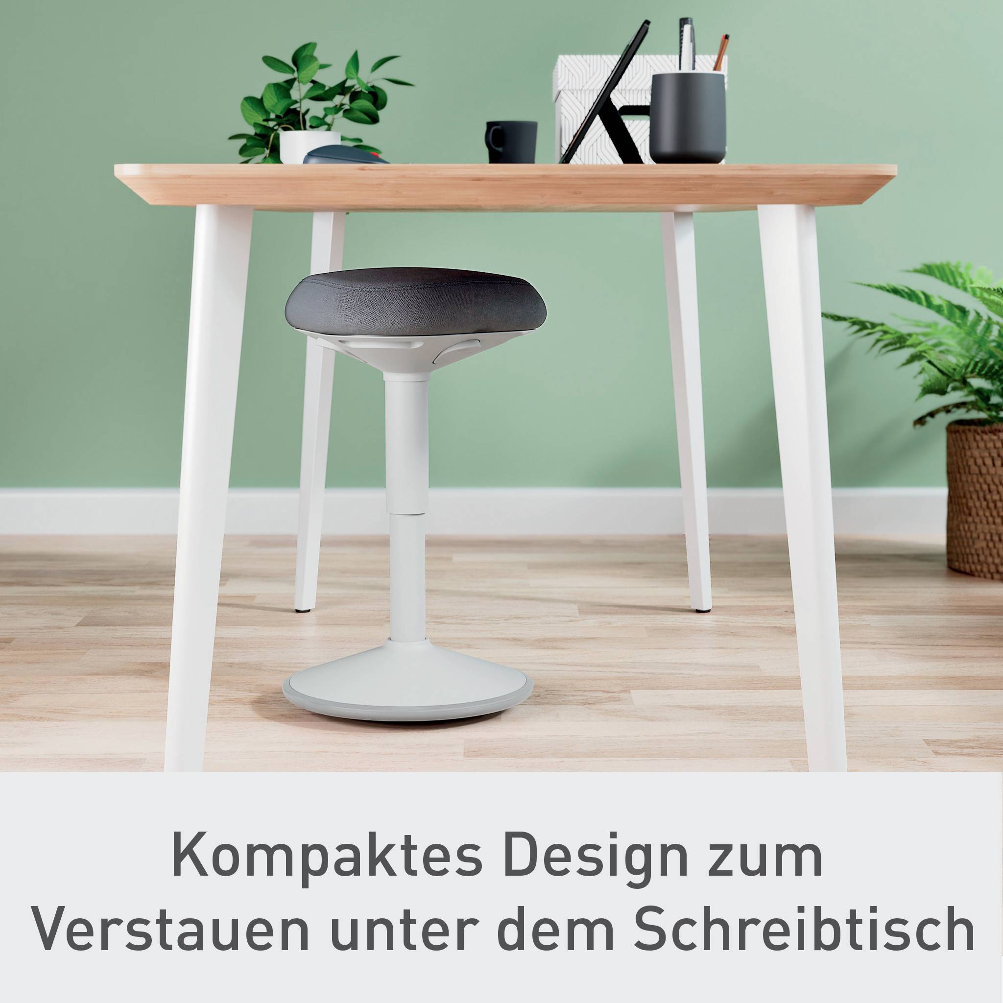 Ein heller, minimalistischer Schreibtisch mit Büromaterialien darauf, darunter ein Stuhl mit rundem Sitz. Text unten: 'Kompaktes Design für Verstauen unter dem Schreibtisch'.