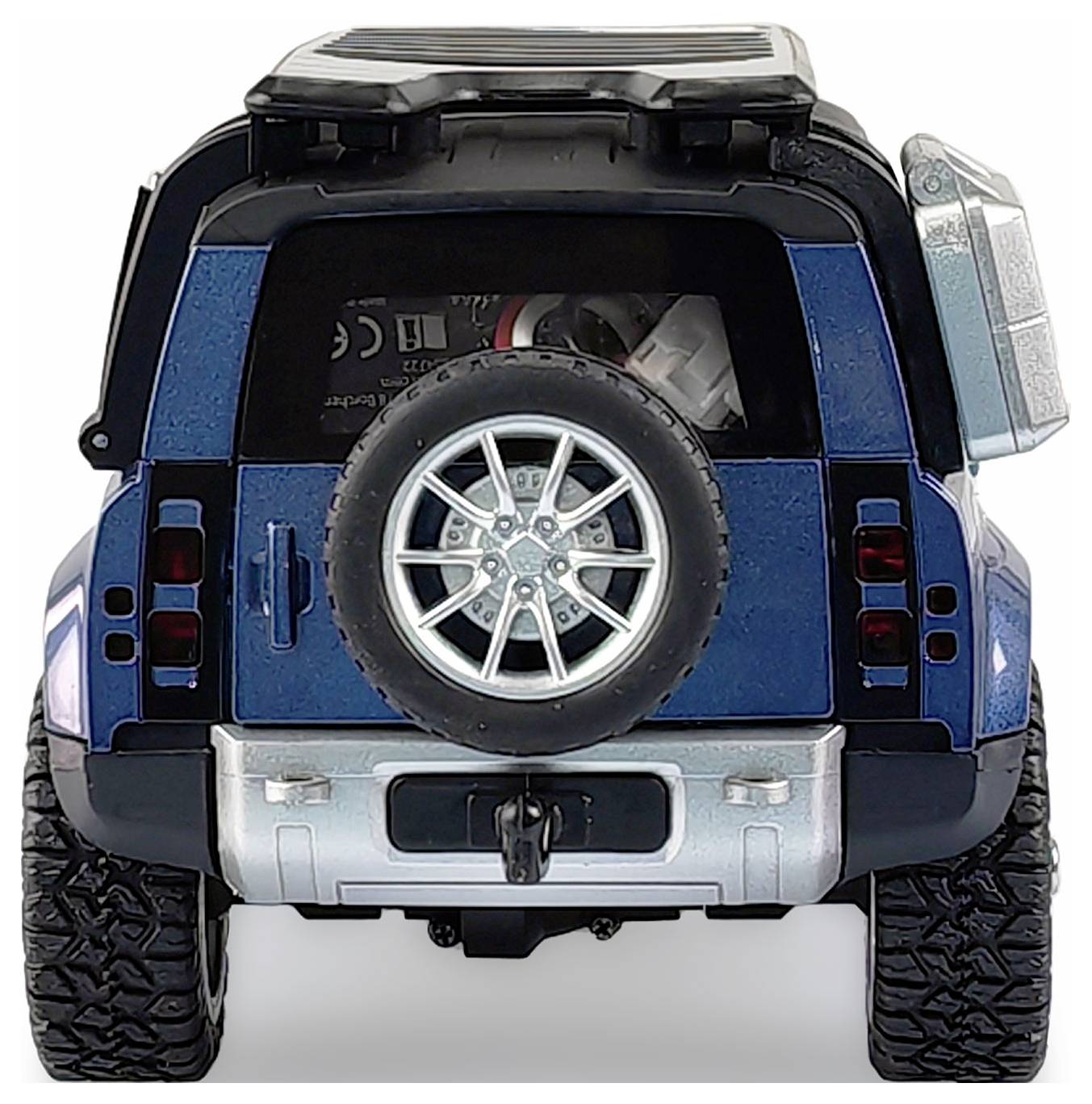 Ein blauer Geländewagen in einer Rückansicht. Ein Ersatzreifen ist an der hinteren Tür montiert. Große Reifen deuten auf Offroad-Fähigkeit hin.