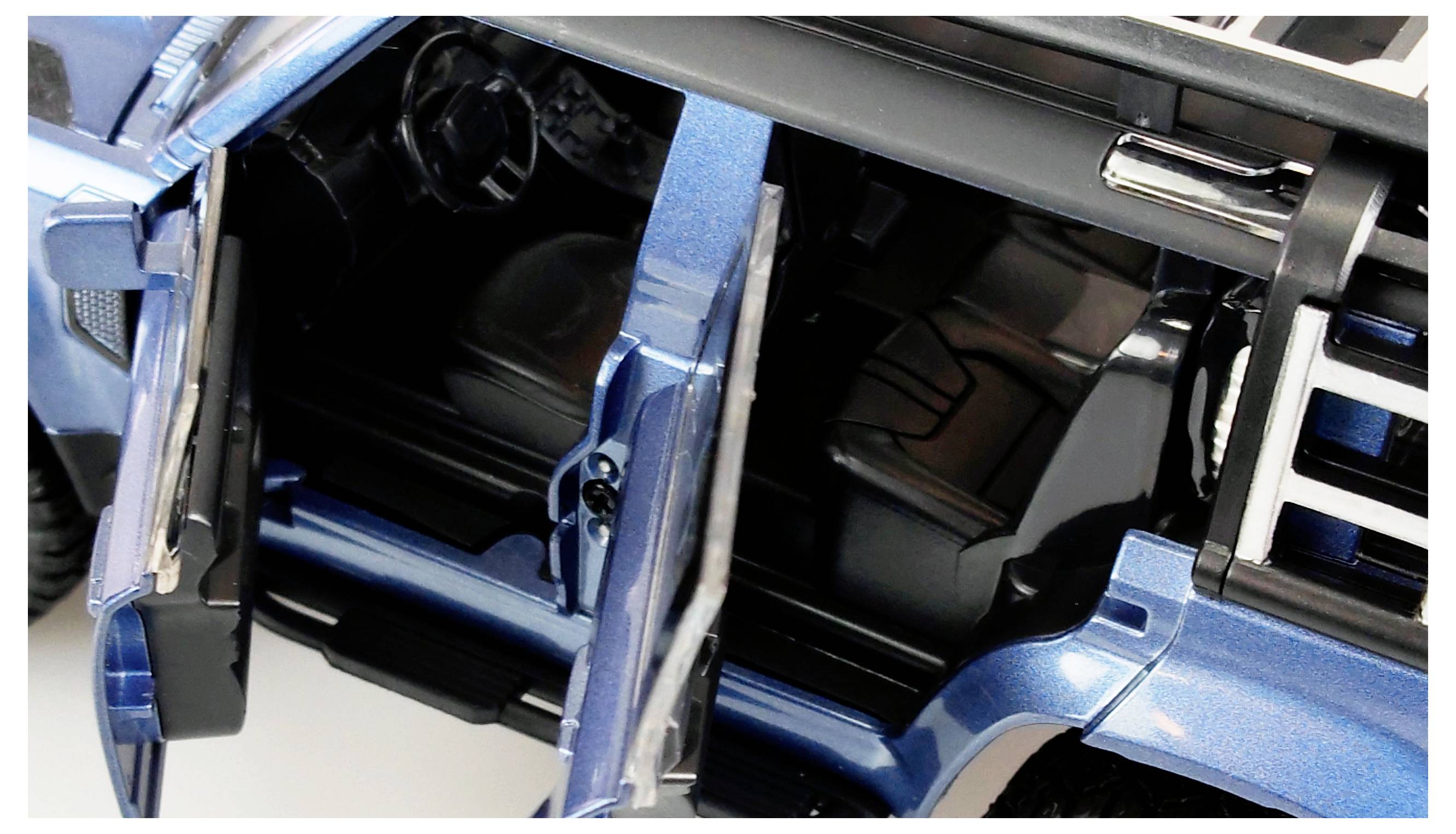 Geöffnetes Modellauto in Blau, zeigt einen Blick auf den Innenraum mit zwei offenen Türen, Lenkrad und Sitzen.