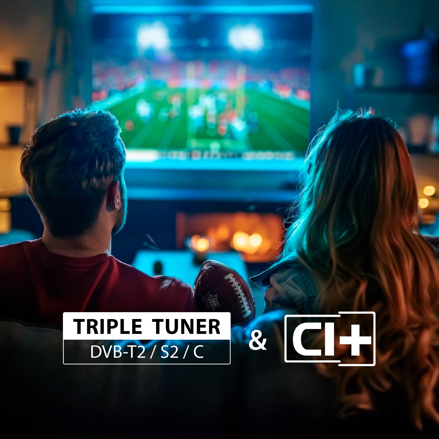 Ein Paar beobachtet ein Fußballspiel im Fernsehen aus einem gemütlichen Wohnzimmer. Das Display zeigt 'TRIPLE TUNER DVB-T2/S2/C & CI+'.