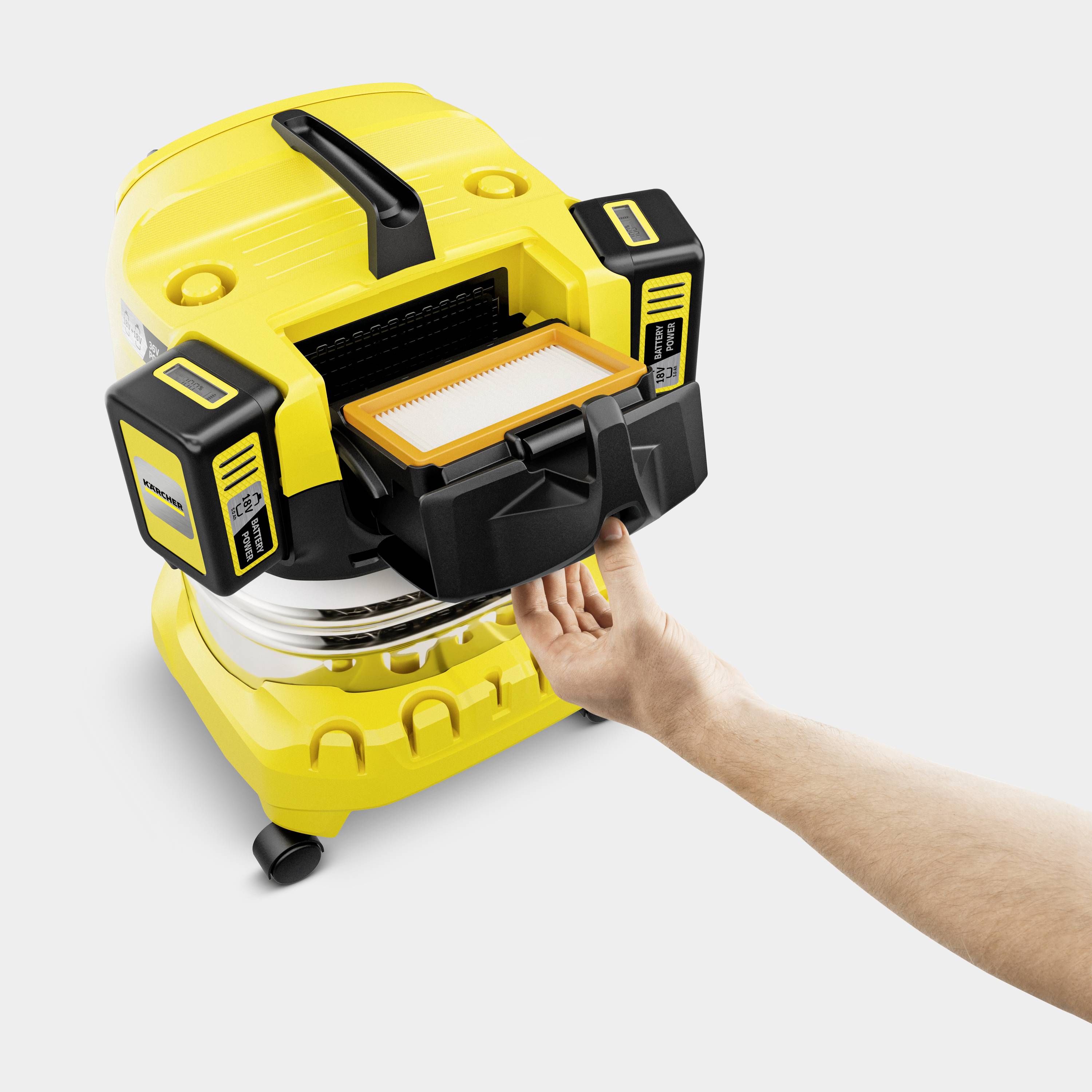 Eine Hand zeigt auf einen gelben Industriestaubsauger mit geöffneter Klappe, die den Filterzugang zeigt.