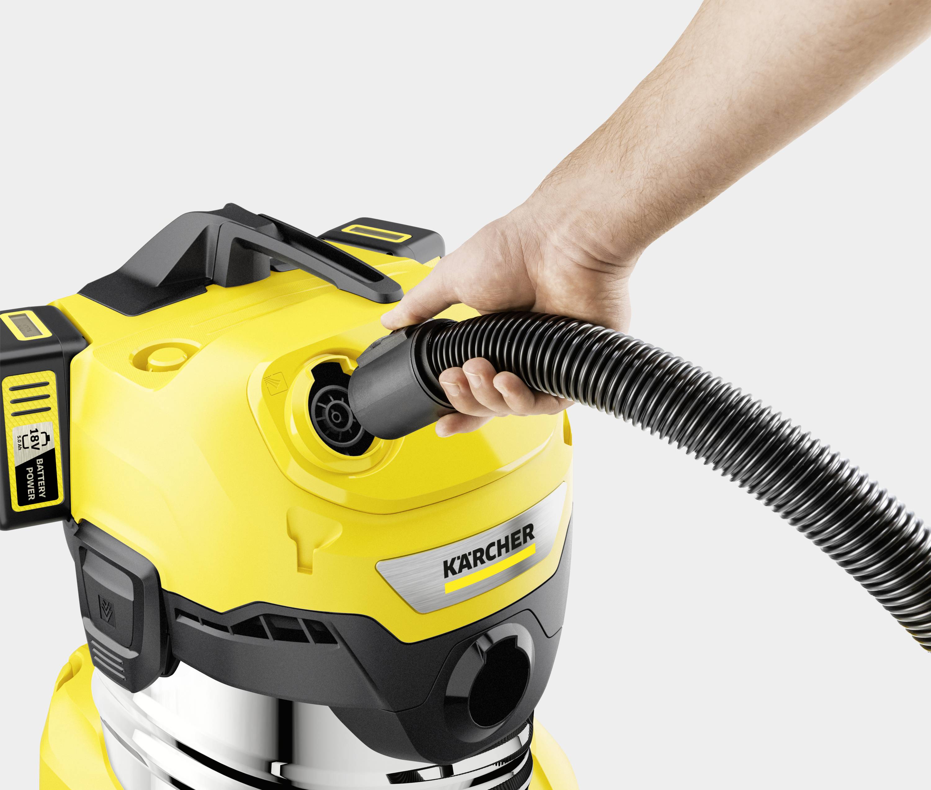Eine Hand steckt einen Schlauch in einen gelben Staubsauger. Der Staubsauger hat silberne und schwarze Details und das Logo 'Kärcher'.