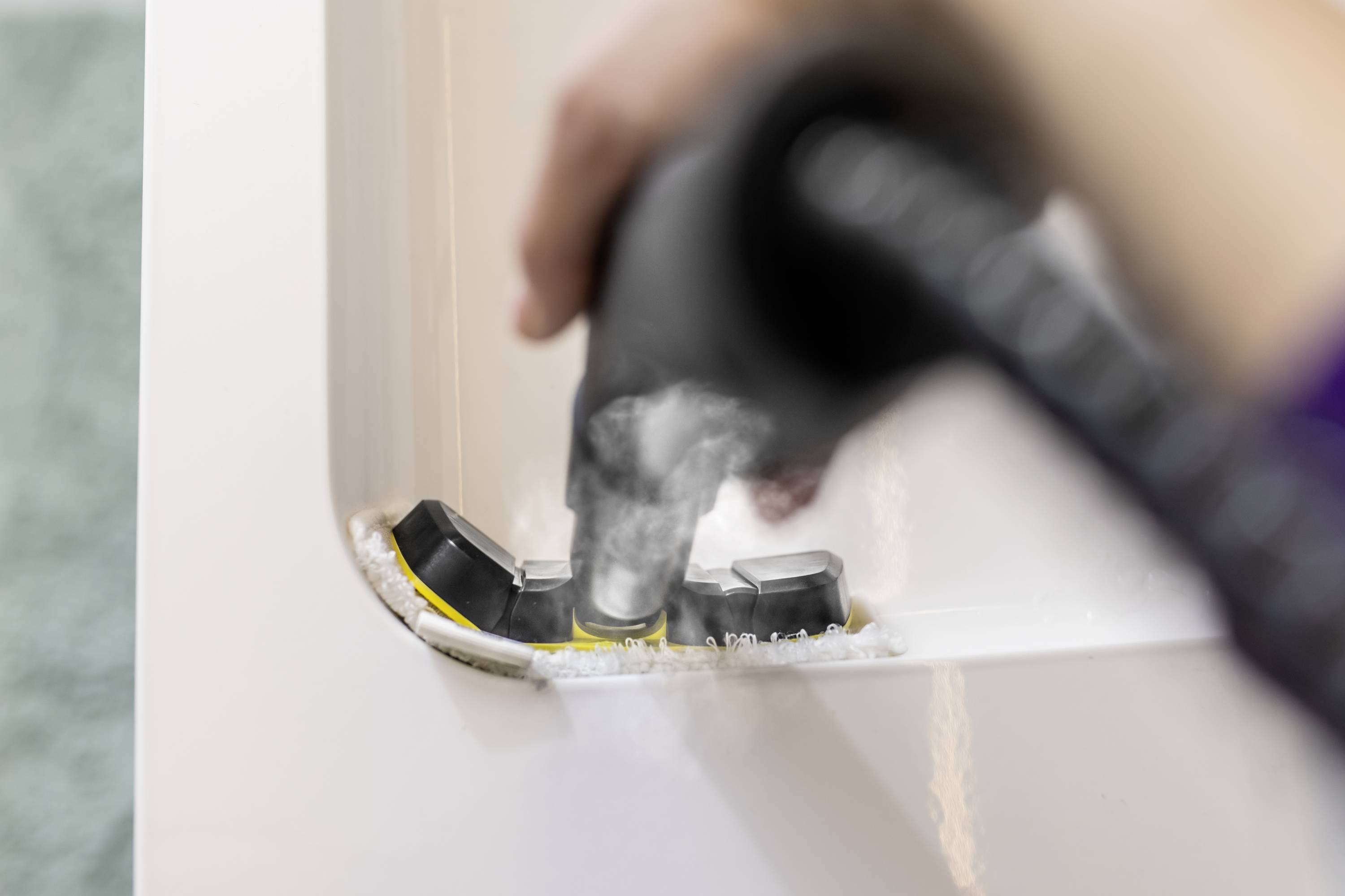 Eine Hand reinigt eine Kaffeemaschine, indem Wasser auf die Dichtungsteile im Inneren gesprüht wird.