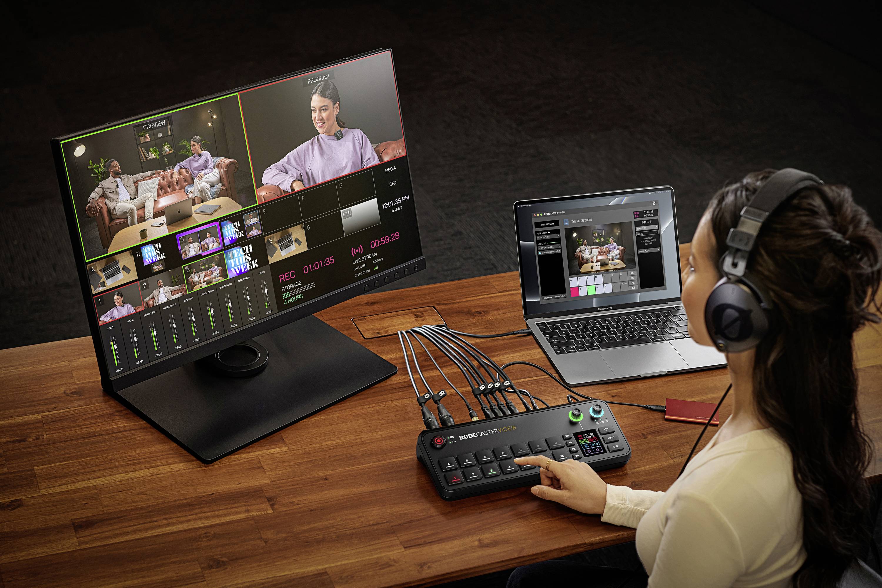 Eine Person sitzt an einem Schreibtisch und bedient ein Videoschnittpult, mit Monitor und Laptop, beide mit Schnittsoftware geöffnet.