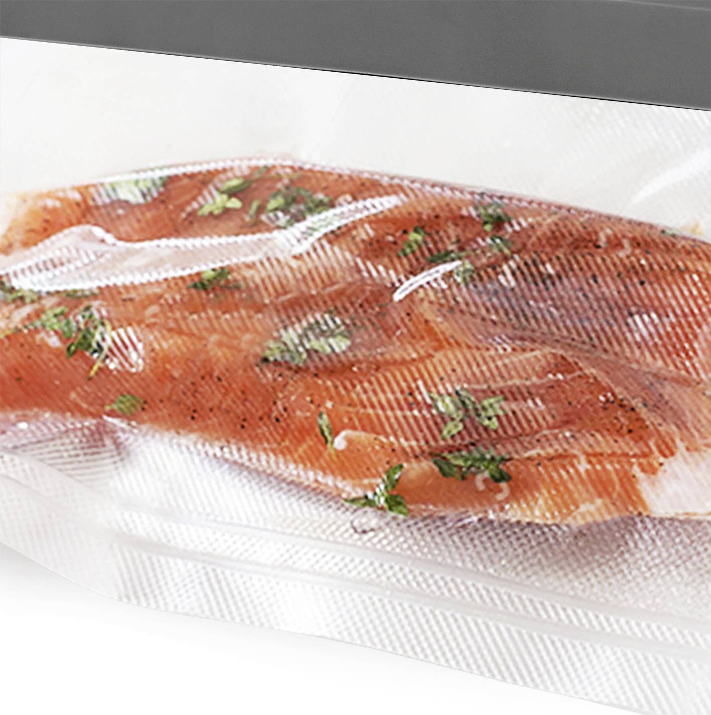 Ein Stück roher, vakuumverpackter Lachs, gewürzt mit Kräutern und Pfeffer, liegt auf einer weißen Oberfläche.