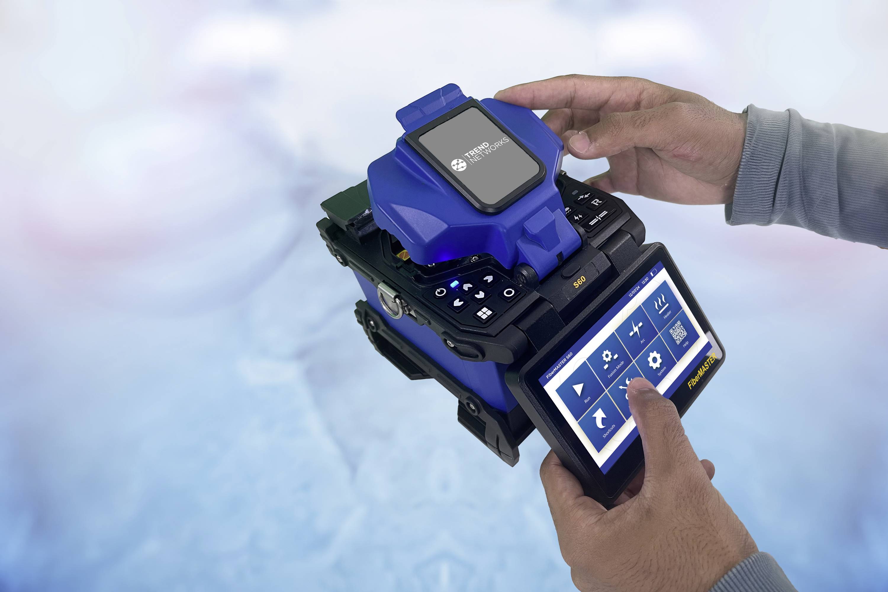 Zwei Hände bedienen ein tragbares Gerät mit Bildschirm und Bedienelementen, möglicherweise für technische Anwendungen oder Messungen.