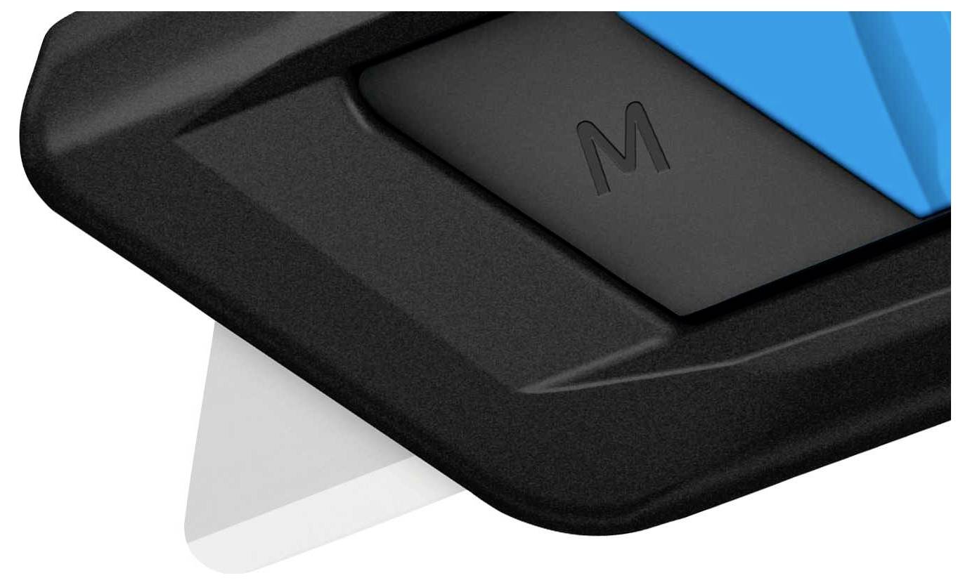 Nahaufnahme einer schwarzen Taste mit der Aufschrift 'M' auf einer Tastatur. Ein blauer Akzent und ein weißes Papiereck sind sichtbar.