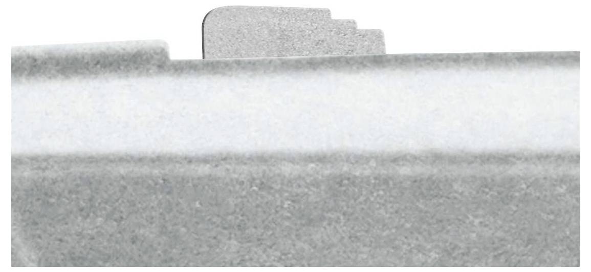 Metallklammer mit abgestufter Kante auf grauem Hintergrund in Nahaufnahme.