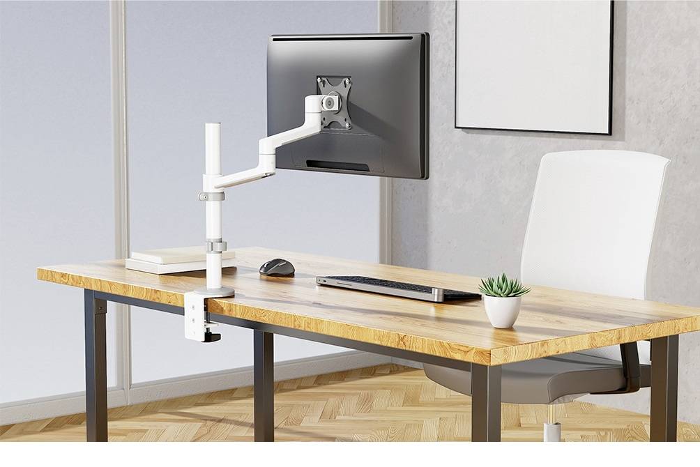 Ein moderner Schreibtisch mit einem Monitorarm, auf dem ein Monitor montiert ist. Daneben stehen eine Tastatur, eine Maus und eine kleine Pflanze.
