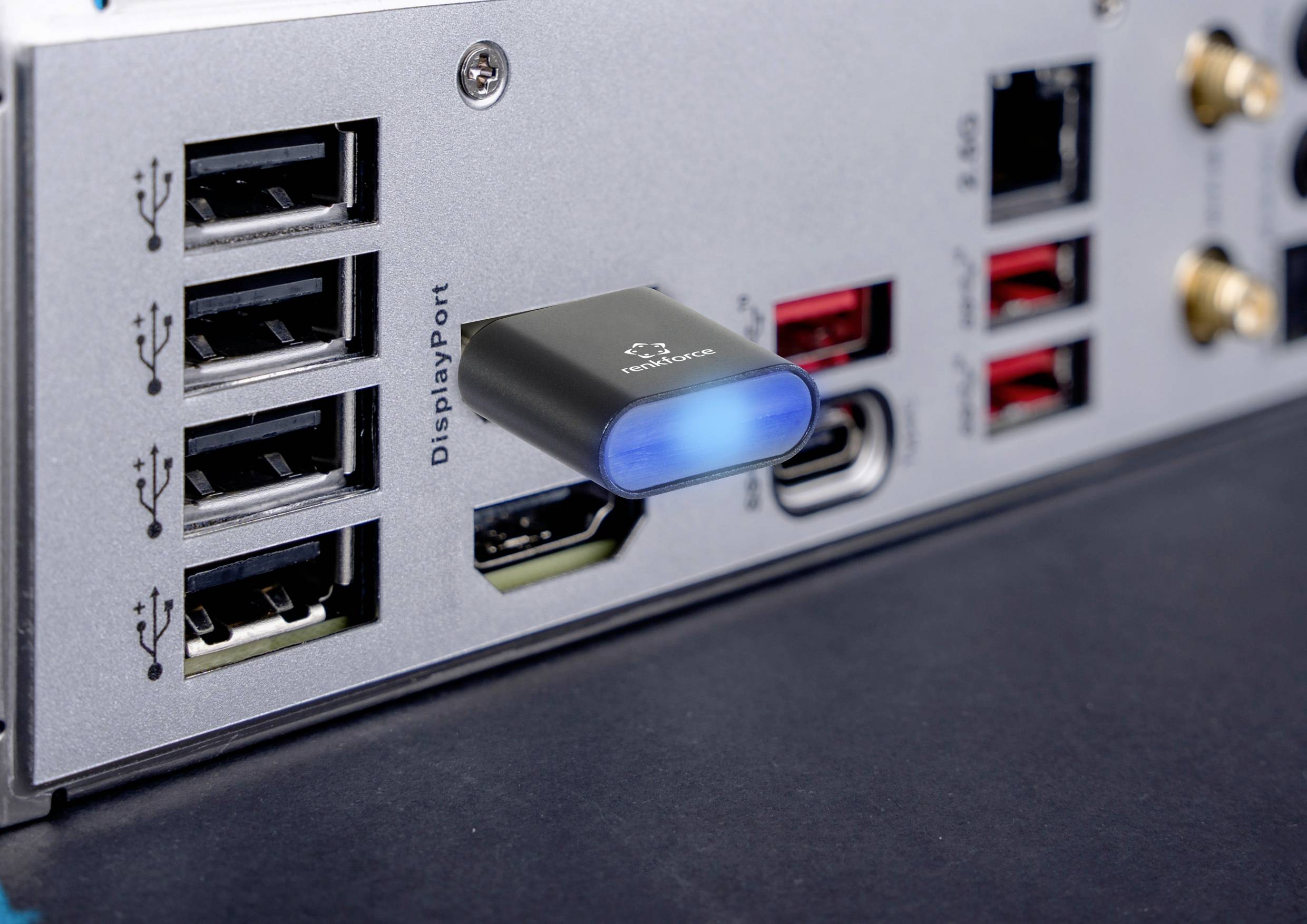 Rückseite eines Computers mit verschiedenen Anschlüssen und einem eingesteckten USB-Stick mit blau leuchtender LED-Anzeige.