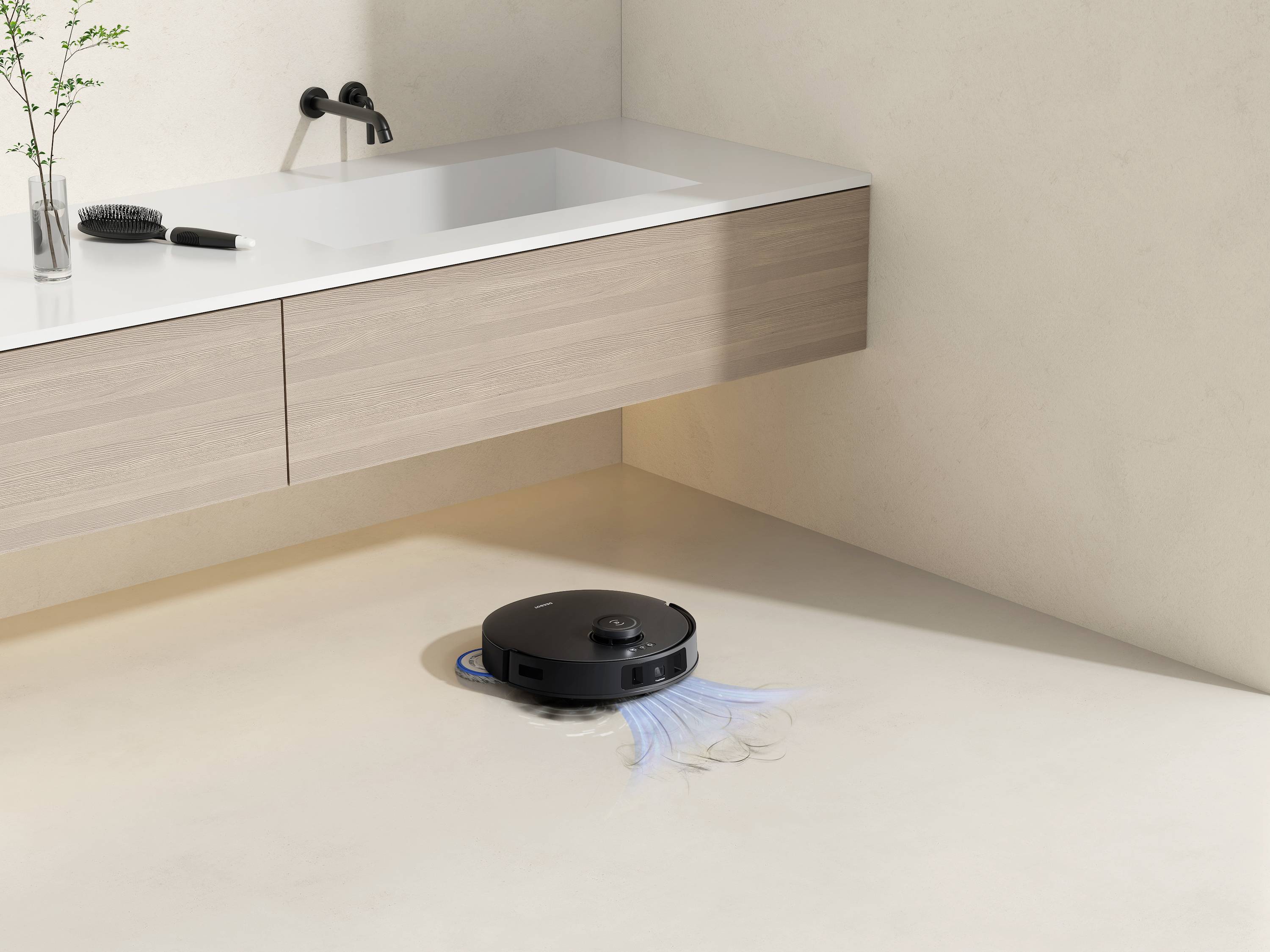 Ein schwarzer Saugroboter reinigt einen hellen, minimalistisch gestalteten Badezimmerboden. Ein Waschbecken und Pflanzen sind sichtbar.