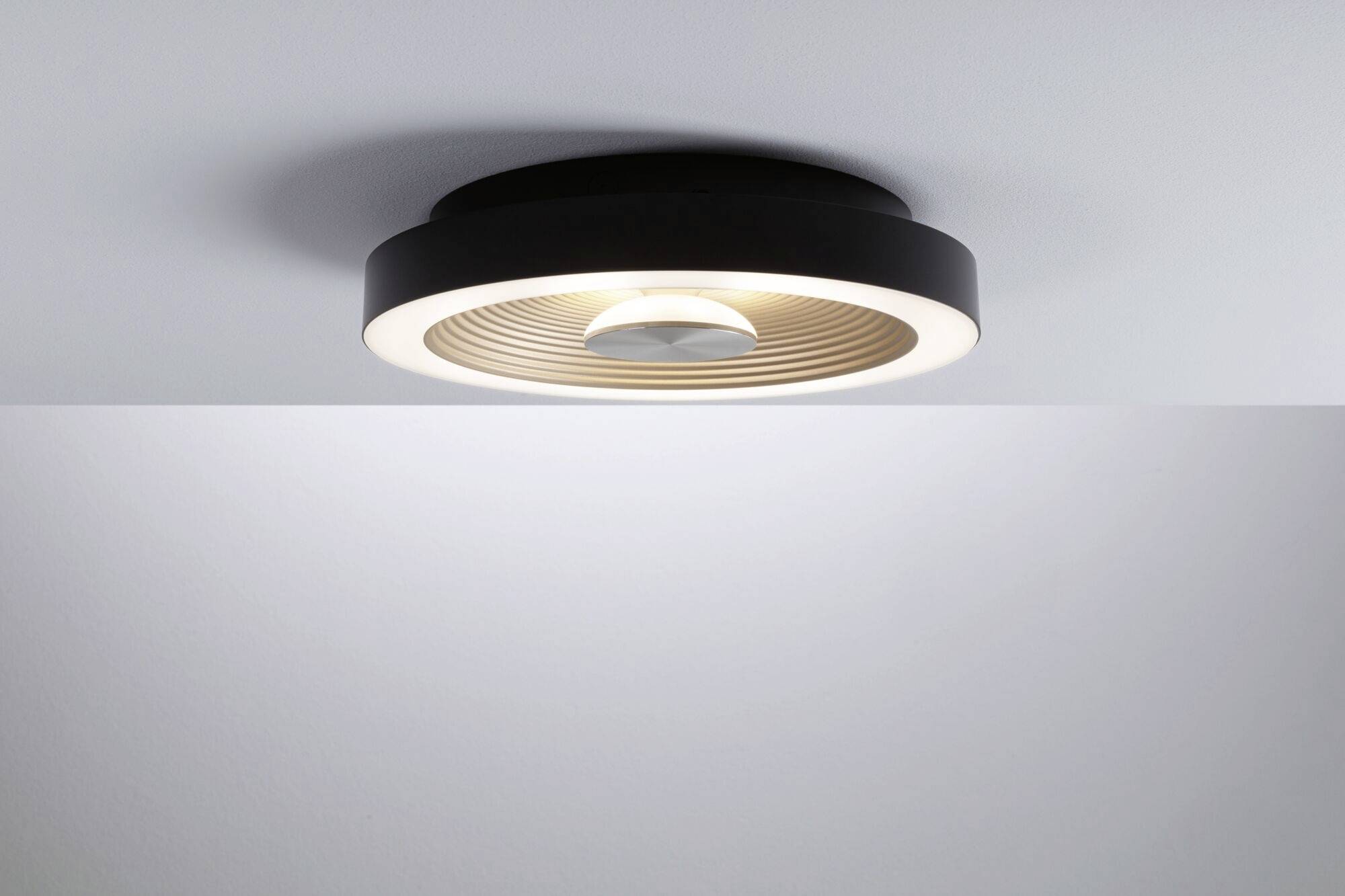 Eine moderne, runde Deckenleuchte mit schwarzem Rand und zentralem Lichtstrahl, montiert an einer weißen Decke.