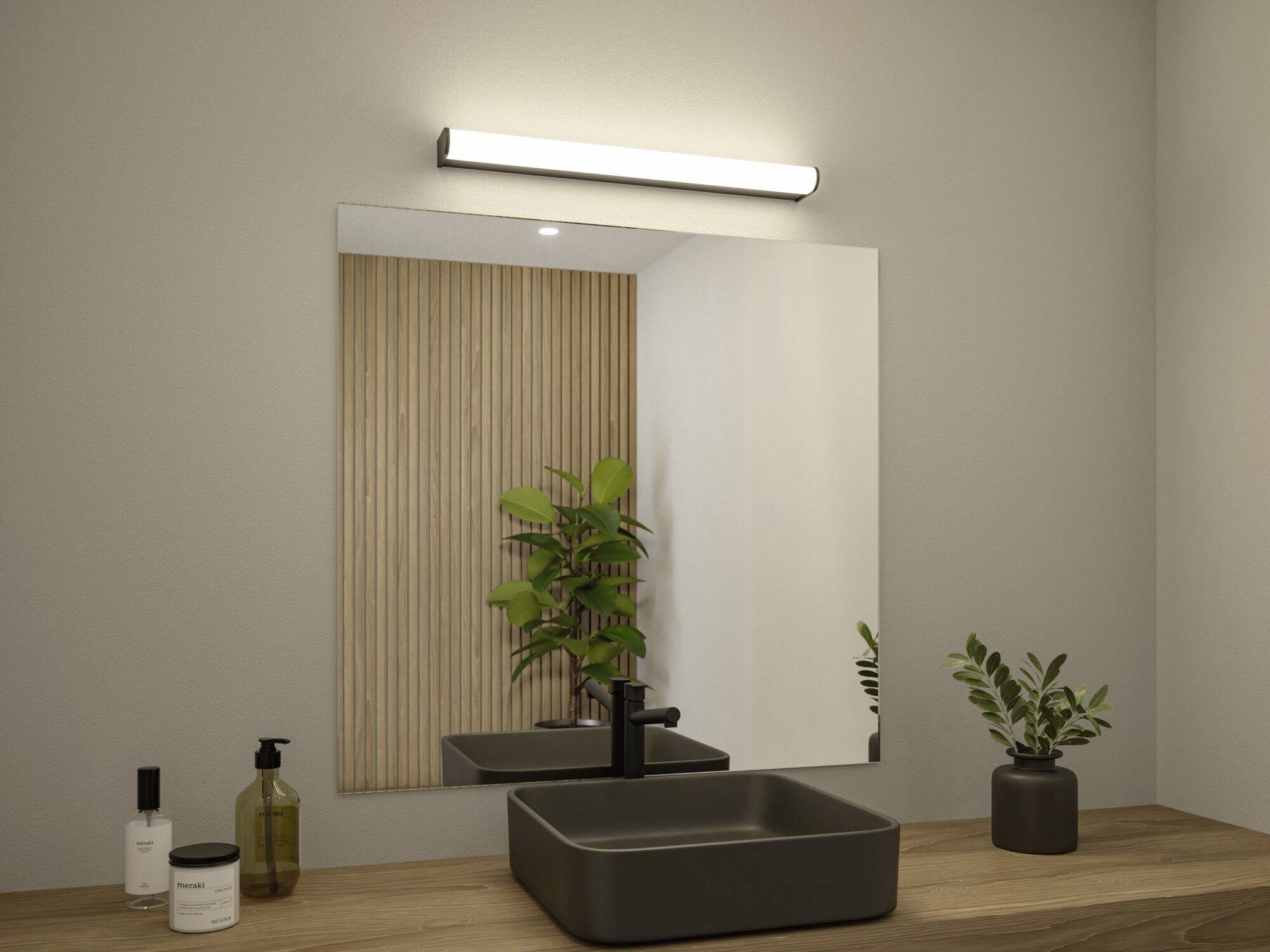 Ein schlichtes Badezimmer mit einem Spiegel, beleuchtetem Wandlicht, Waschbecken und Pflanzen auf einem Holztresen.