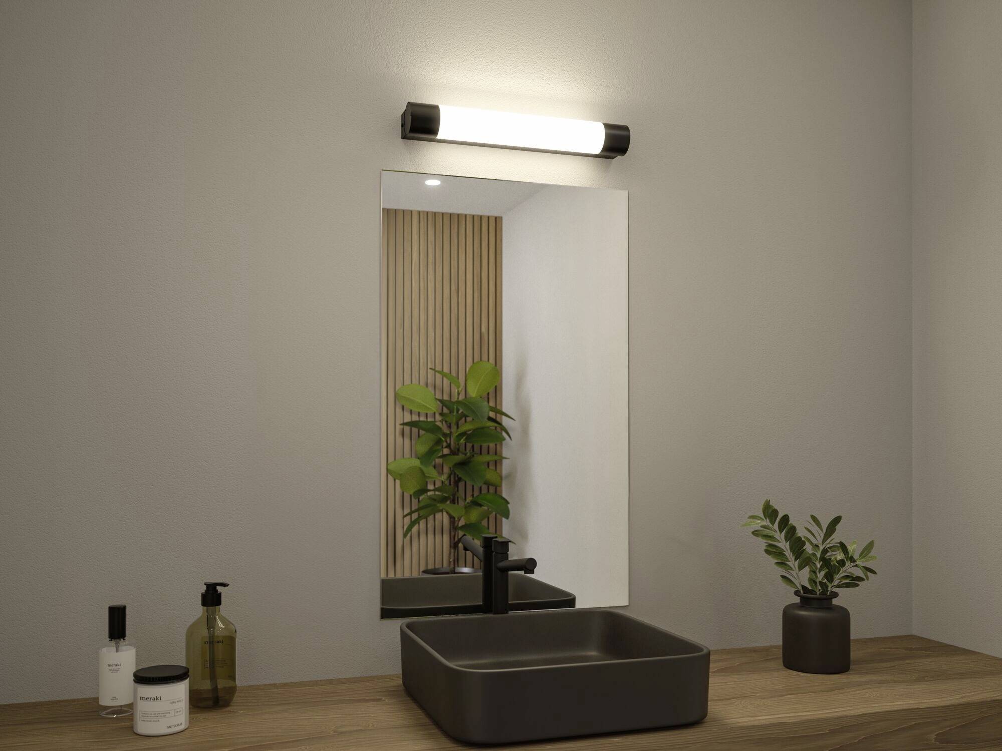 Ein schlichtes Badezimmer mit Holzregal, rechteckigem Spiegel, schwarzem Waschbecken und moderner Beleuchtung; links Pflanzen und Seifenspender.