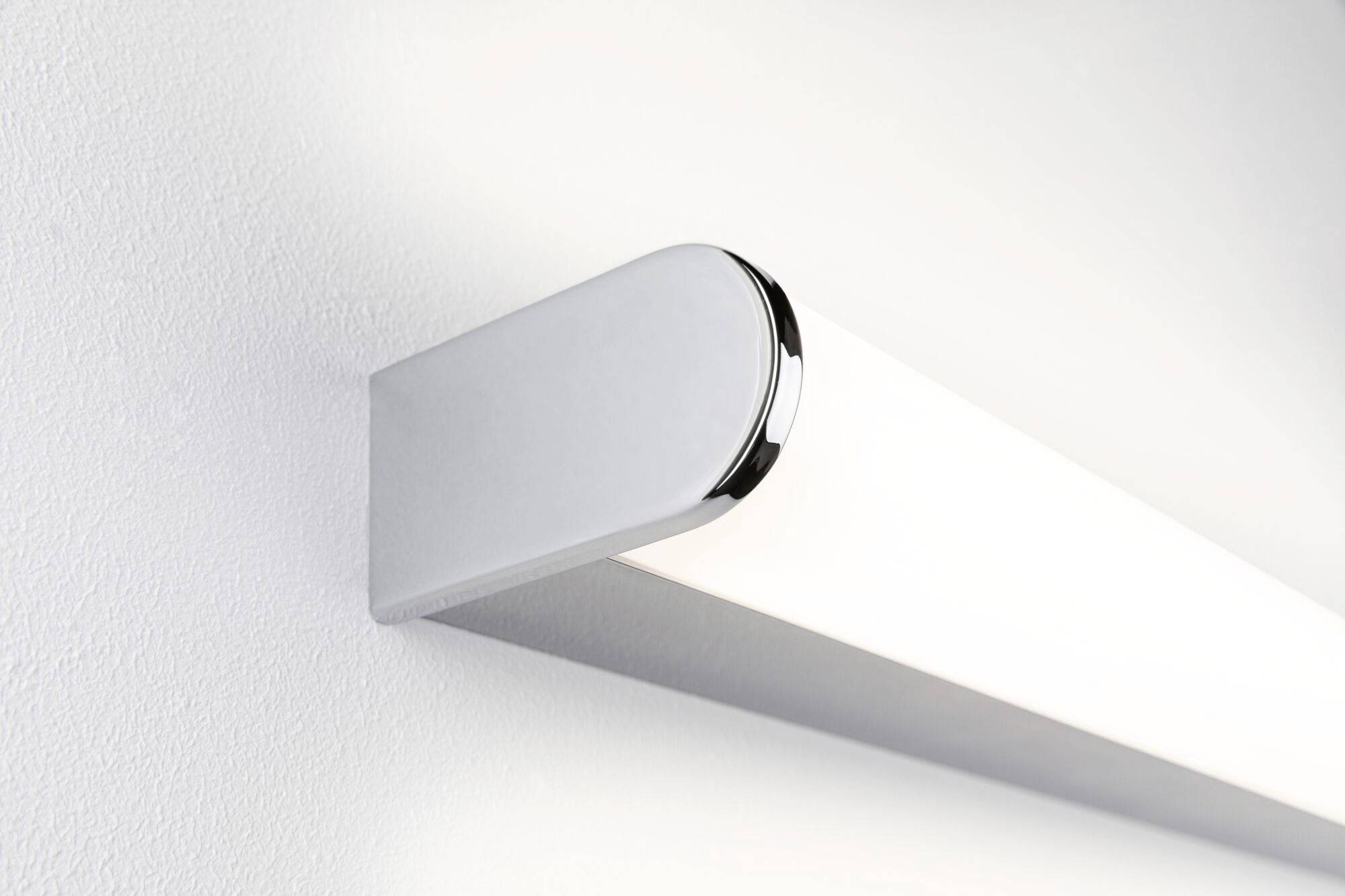 Ein modernes, längliches LED-Licht an einer weißen Wand montiert, strahlt helles, gleichmäßiges Licht aus. Geeignet für minimalistische Innenräume.