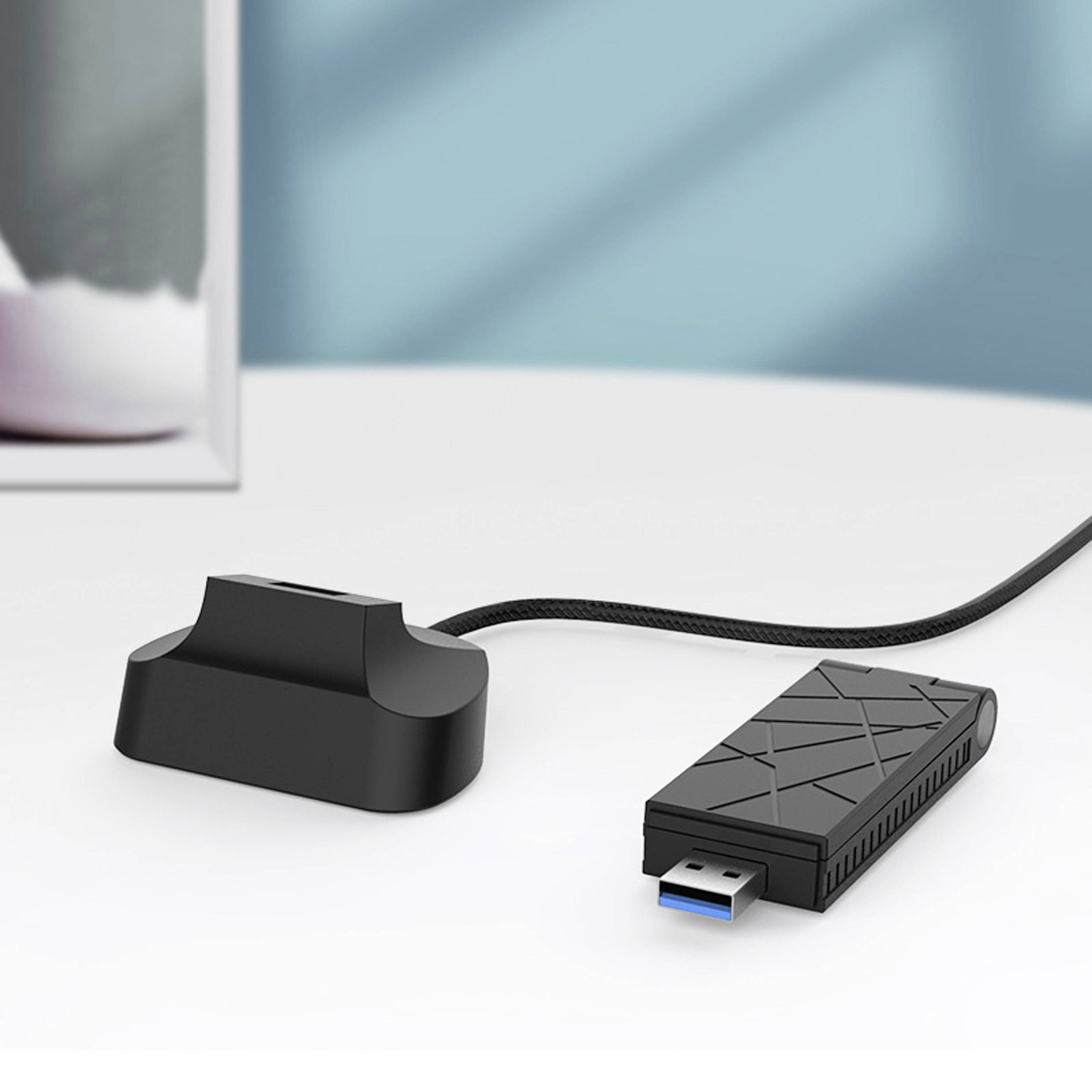 Ein USB-Adapter mit strukturiertem Gehäuse liegt auf einer weißen Oberfläche, verbunden mit einer kleinen, schwarzen Dockingstation.