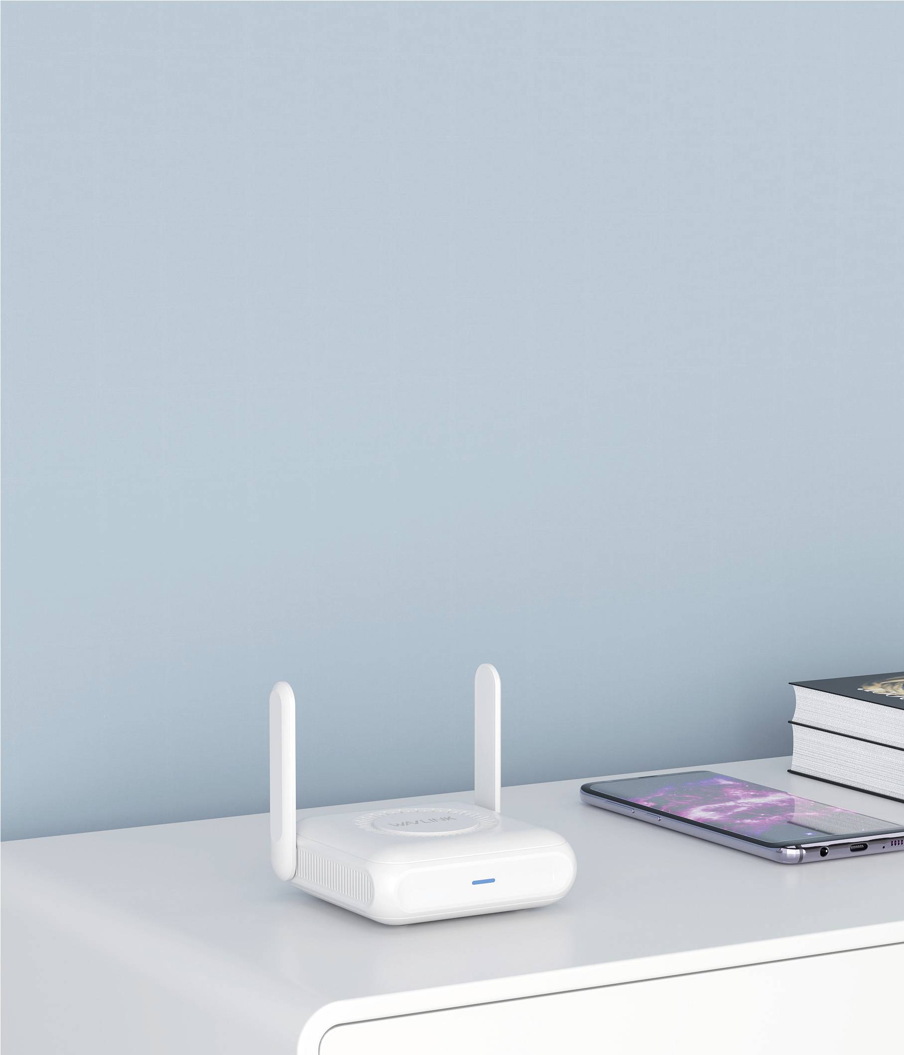 Ein weißer WLAN-Router mit zwei Antennen steht auf einem weißen Tisch neben einem Smartphone und Büchern vor einer blauen Wand.