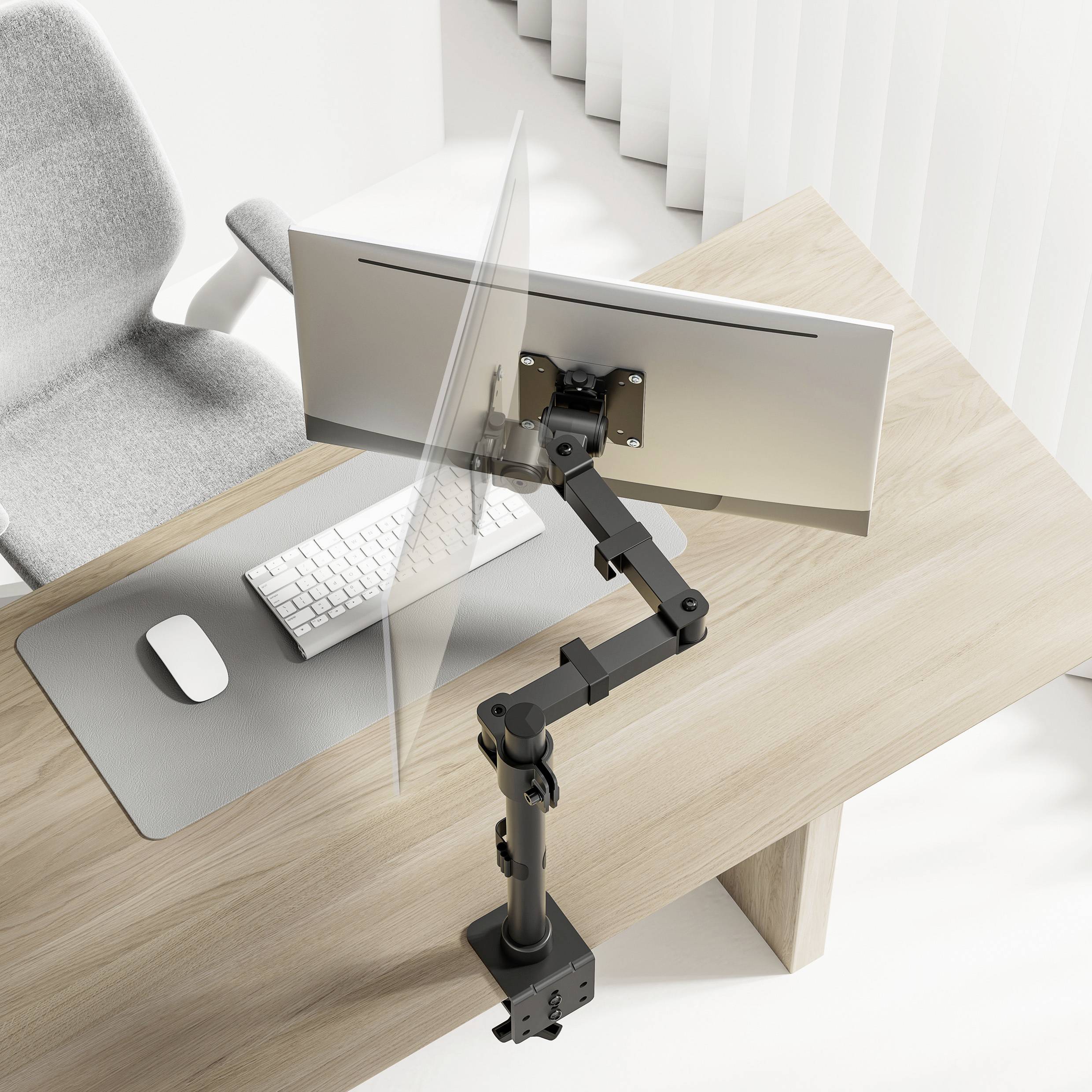 Ein Schreibtisch mit einer ergonomischen Monitorhalterung, die einen Bildschirm über einer Tastatur und Maus hält. Ein grauer Bürostuhl steht daneben.