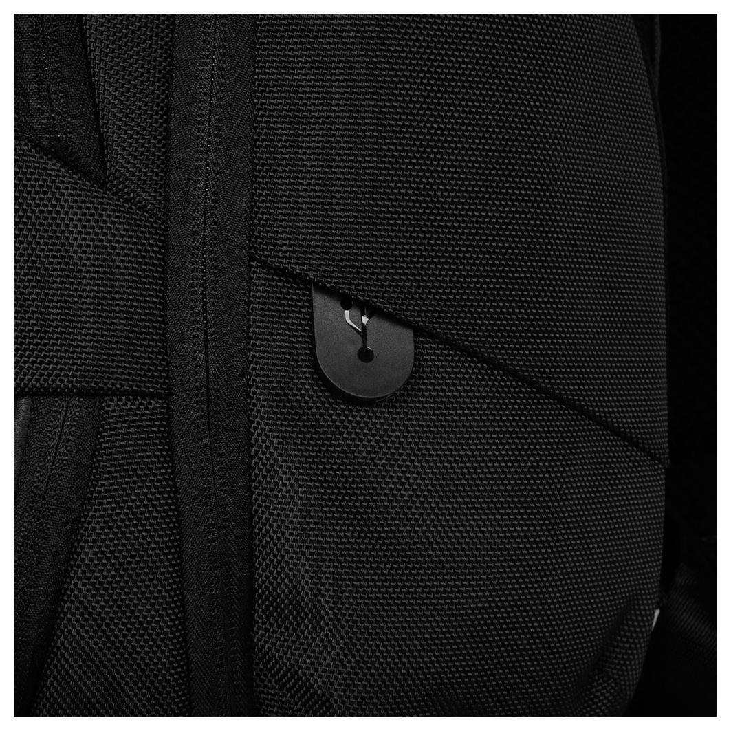 Nahaufnahme eines schwarzen, strukturierten Rucksacks mit einem kleinen Metallhaken an der Seite.