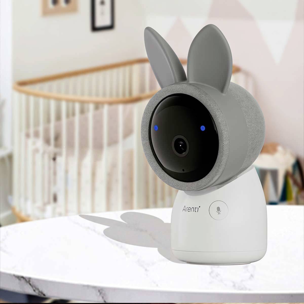 Eine Baby-Kamera in Hasenform steht auf einem Tisch. Im Hintergrund ist ein Kinderbett zu sehen, das auf ein Kinderzimmer hindeutet.