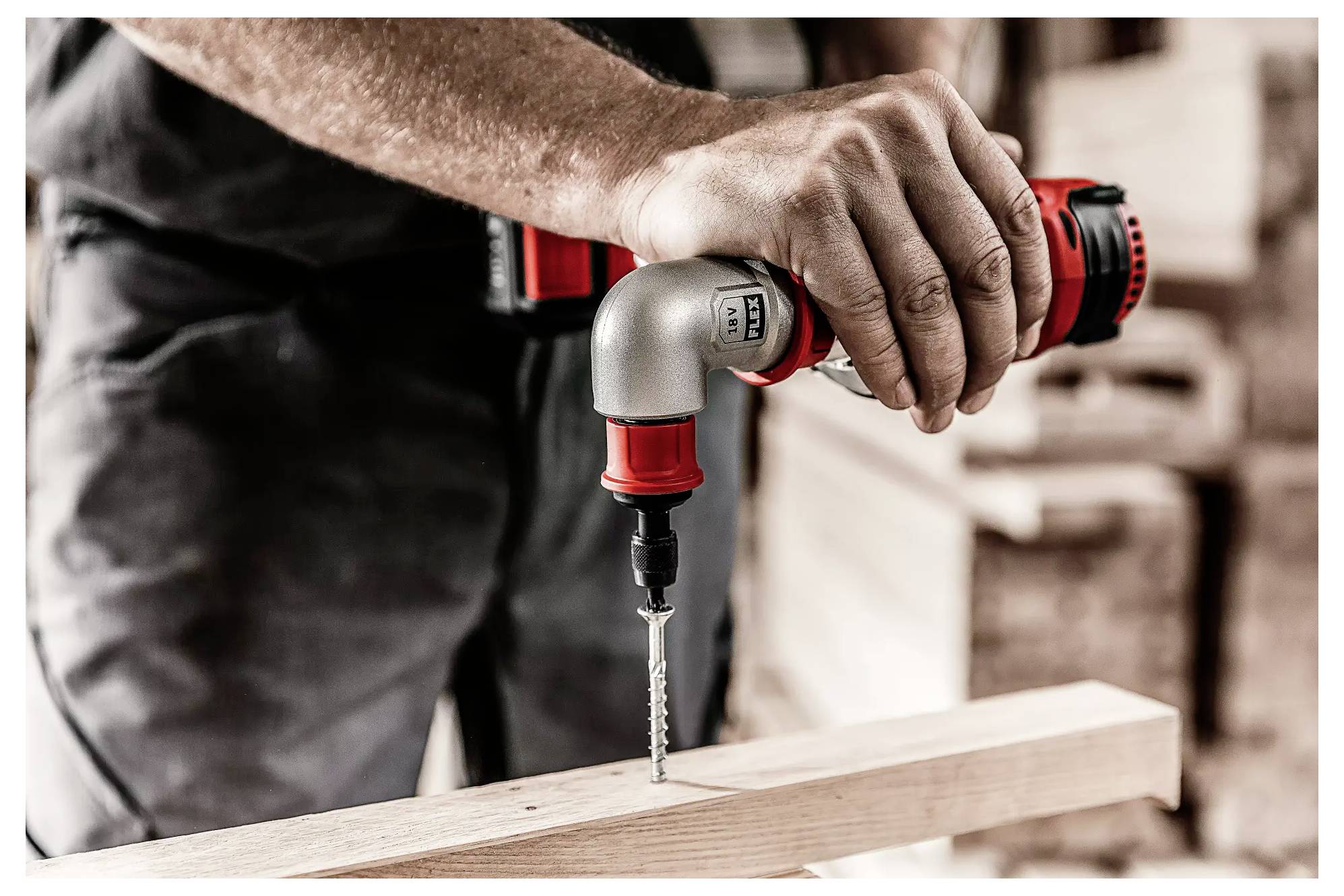 Person arbeitet mit einem Akkuschrauber an einem Holzbrett in einer Werkstatt. Die Bohrmaschine wird von einer Hand gehalten.