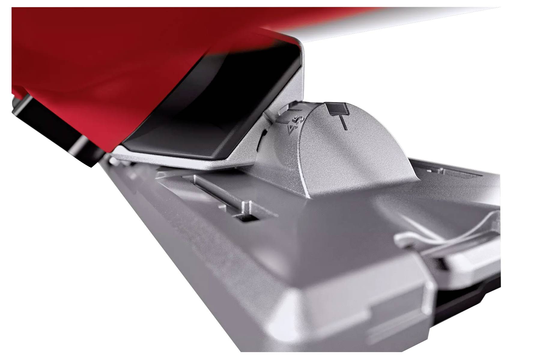 Eine silberne Ski-Bindung, leicht angewinkelt, zeigt den Fersenmechanismus und Einstellmarkierungen, teilweise mit einem roten Schuh verdeckt.