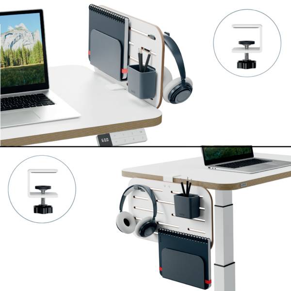 Laptop auf einem höhenverstellbaren Schreibtisch mit Wandtafel, Kopfhörer und Schreibutensilien; fokussiert auf Organisation.