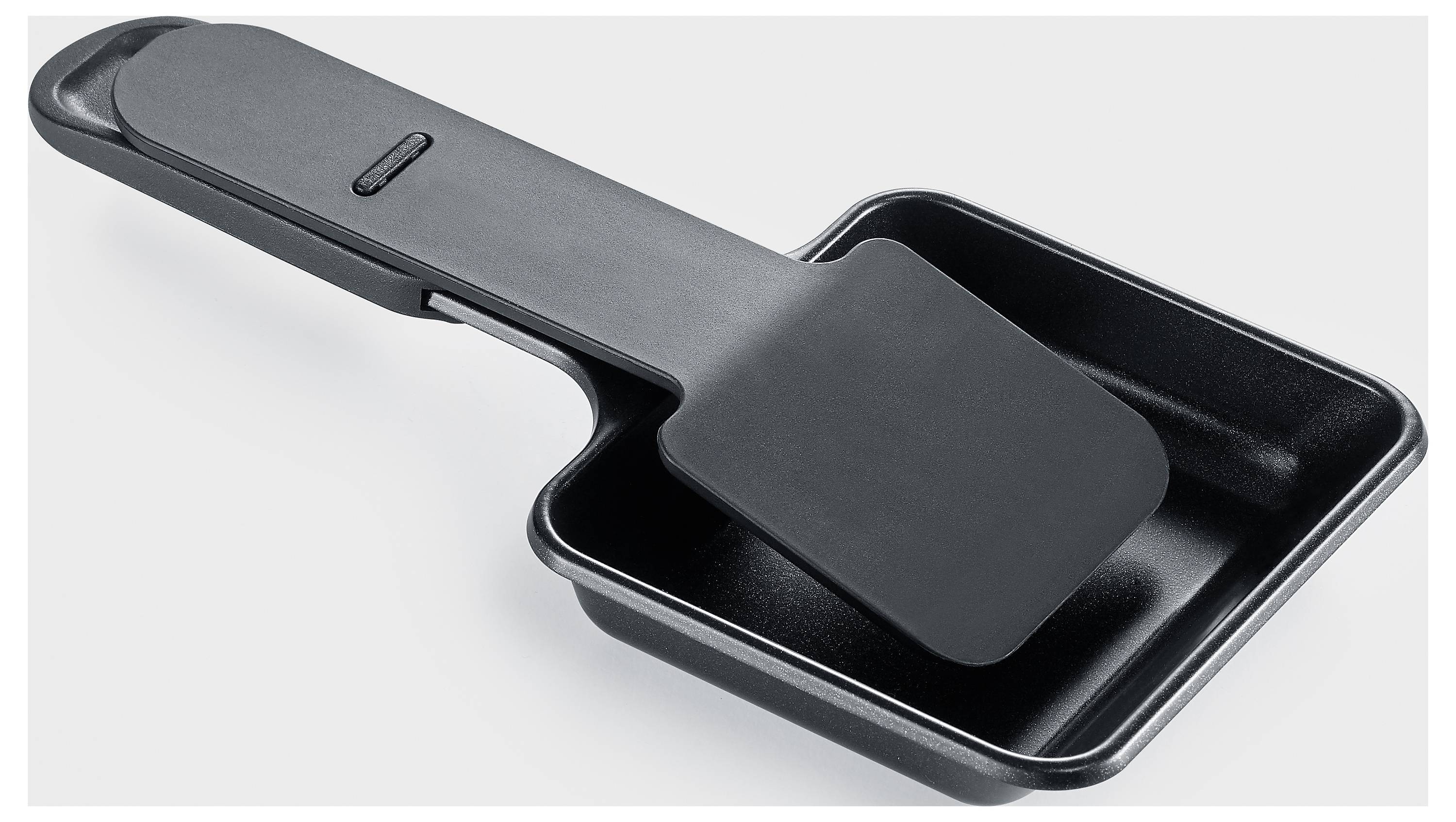 Eine schwarze Raclette-Pfanne mit integriertem Spatel, geeignet zum Schmelzen von Käse oder Grillen kleiner Speisen.