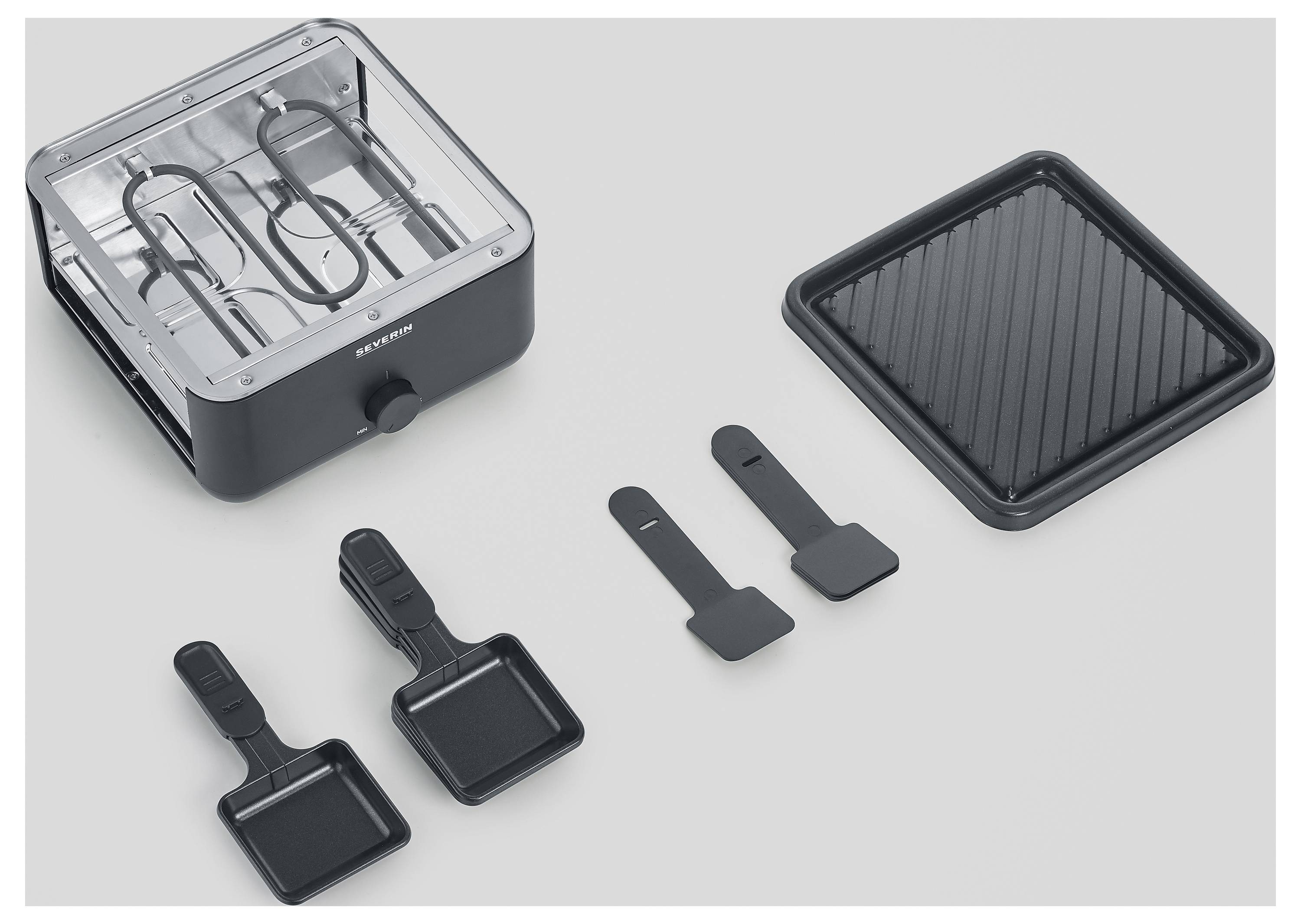 Ein schwarzer Raclette-Grill mit zwei Pfännchen, zwei Spachteln und einer geriffelten Grillplatte. Perfekt für gemütliche Abende.