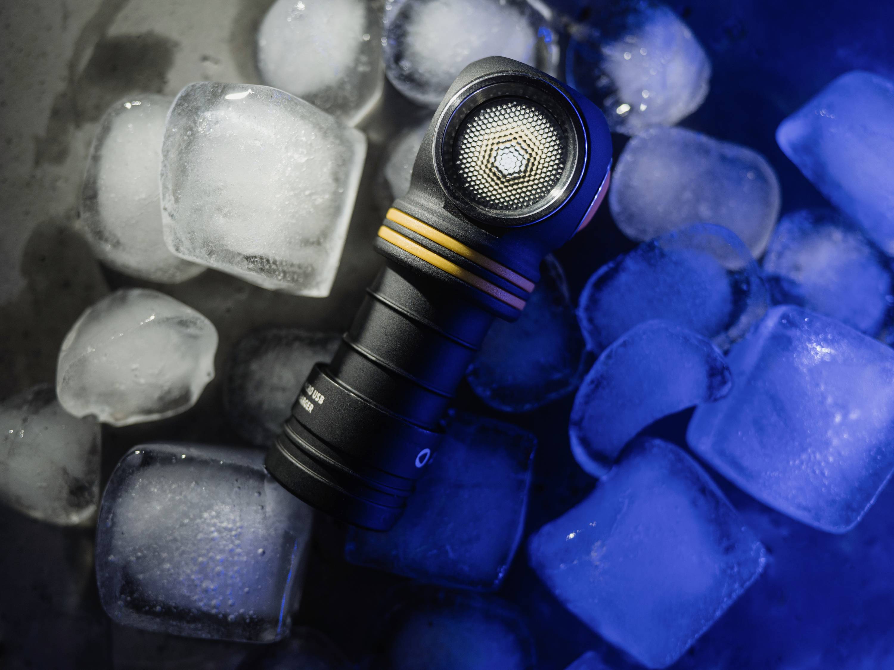 Taschenlampe liegt auf Eiswürfeln, beleuchtet in blauem Licht.
