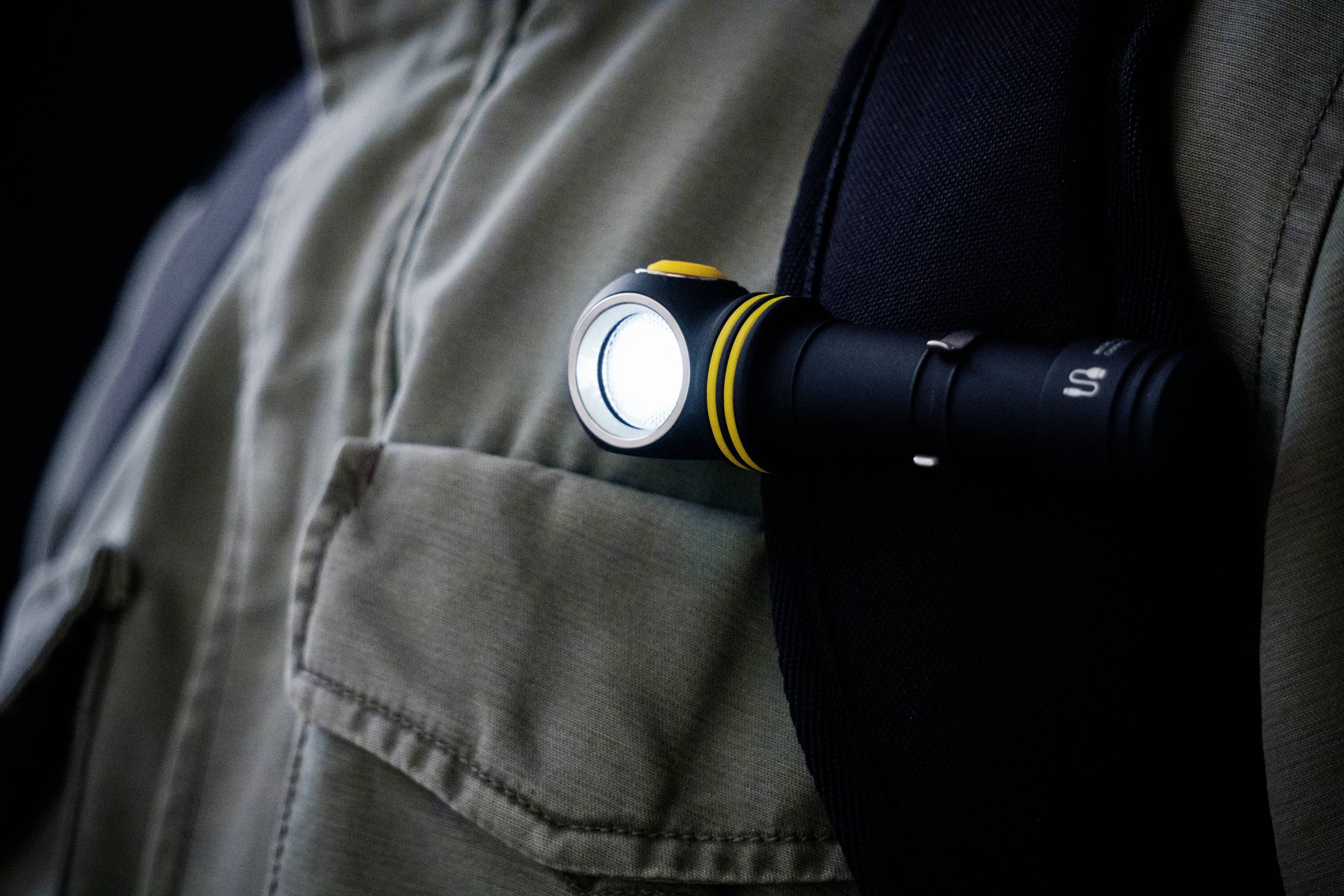 Eine Taschenlampe ist an einem Rucksackriemen befestigt, leuchtet hell und bietet Beleuchtung beim Gehen im Dunkeln.