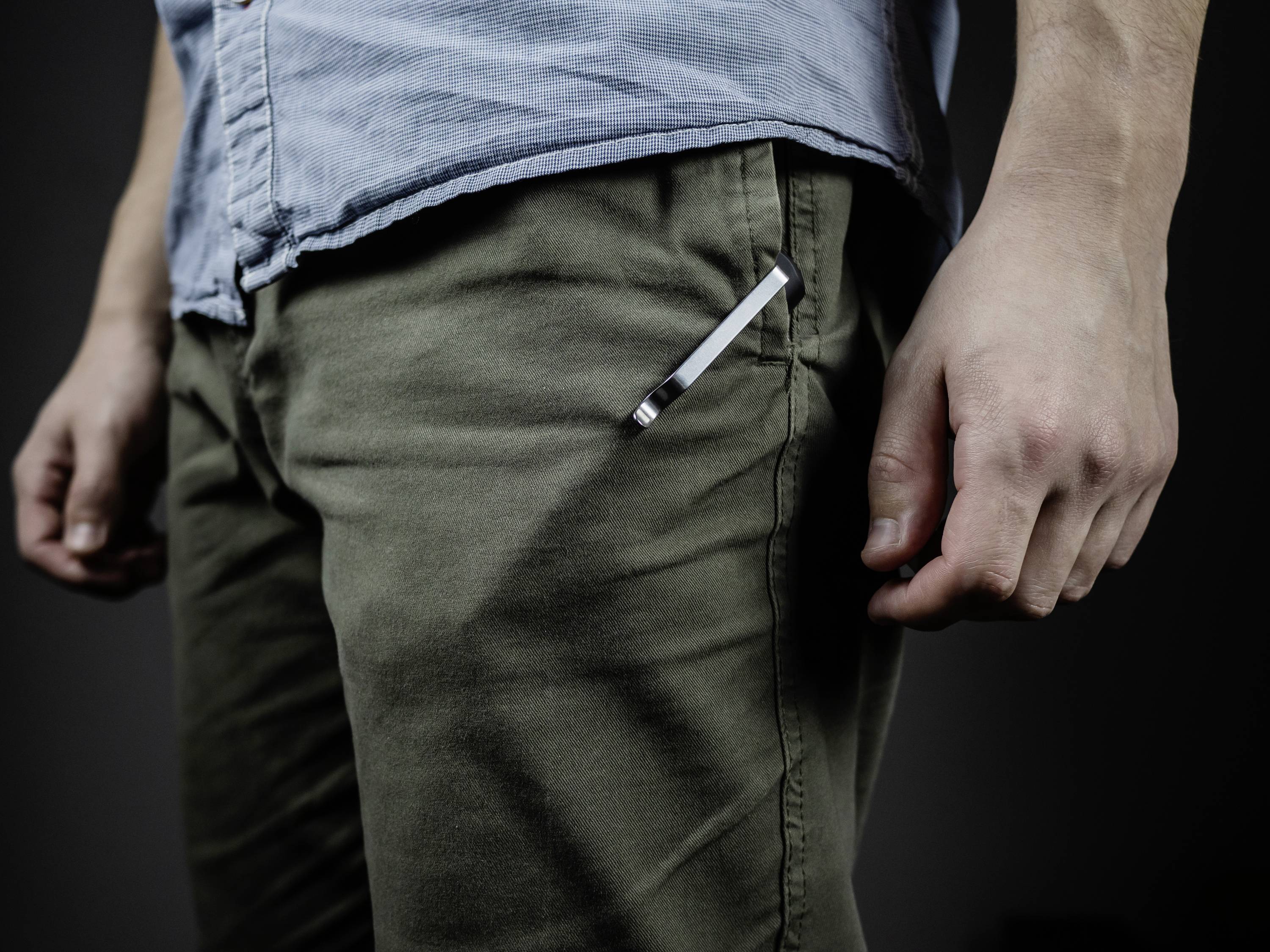 Ein Mann trägt eine blaue Hemd und grüne Hose. Ein Stift steckt in der Hosentasche. Der Fokus liegt auf der unteren Körperhälfte.