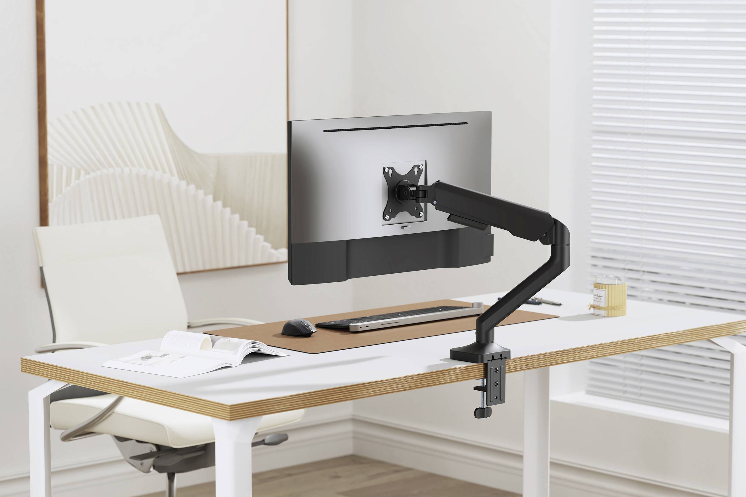 Ein moderner, aufgeräumter Arbeitsplatz mit einem einstellbaren Monitorarm und einem Flachbildschirm auf einem weißen Schreibtisch.