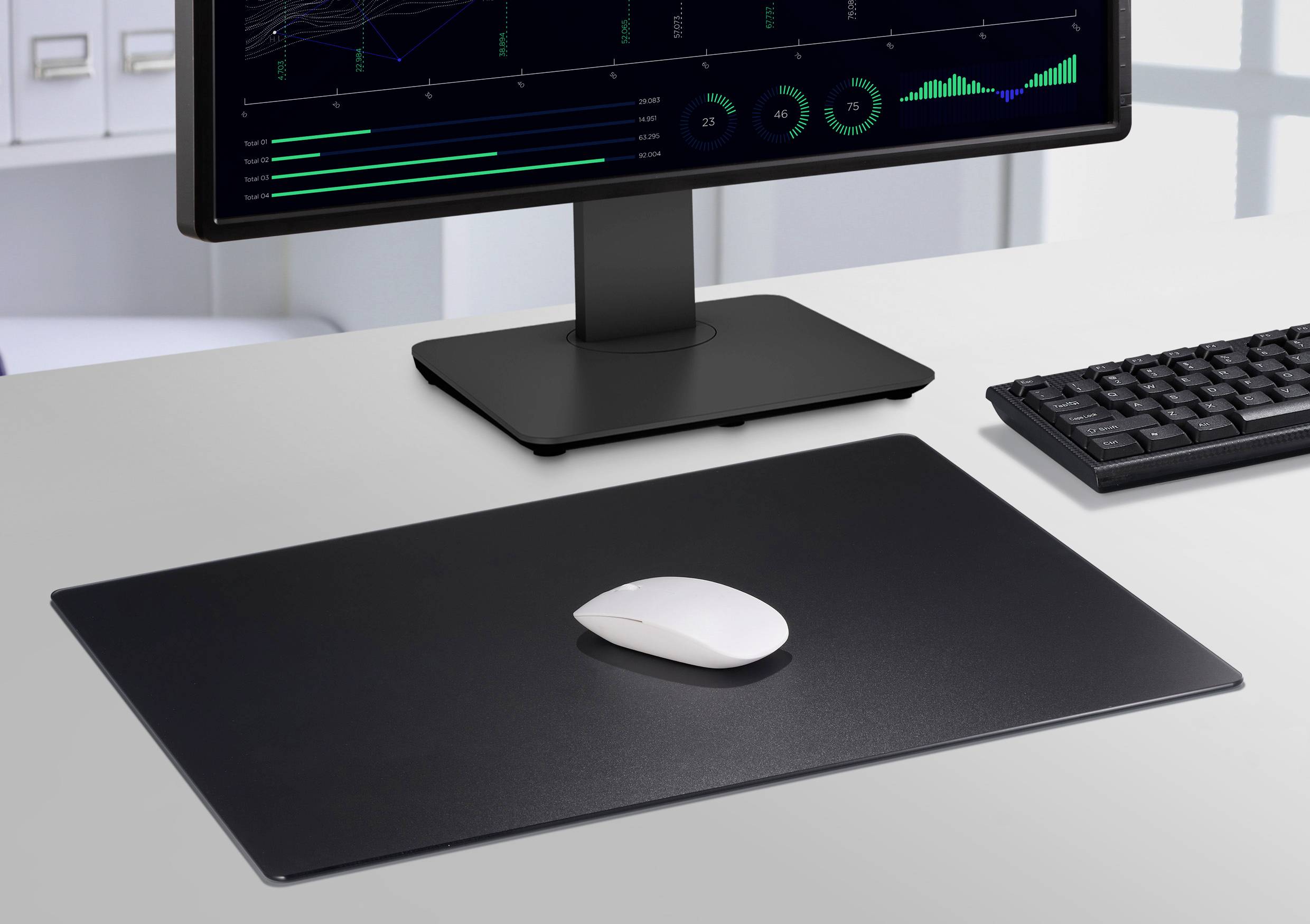 Ein Schreibtisch mit Computerbildschirm, Tastatur und Maus auf einem großen Mousepad. Der Bildschirm zeigt Datenvisualisierungen.