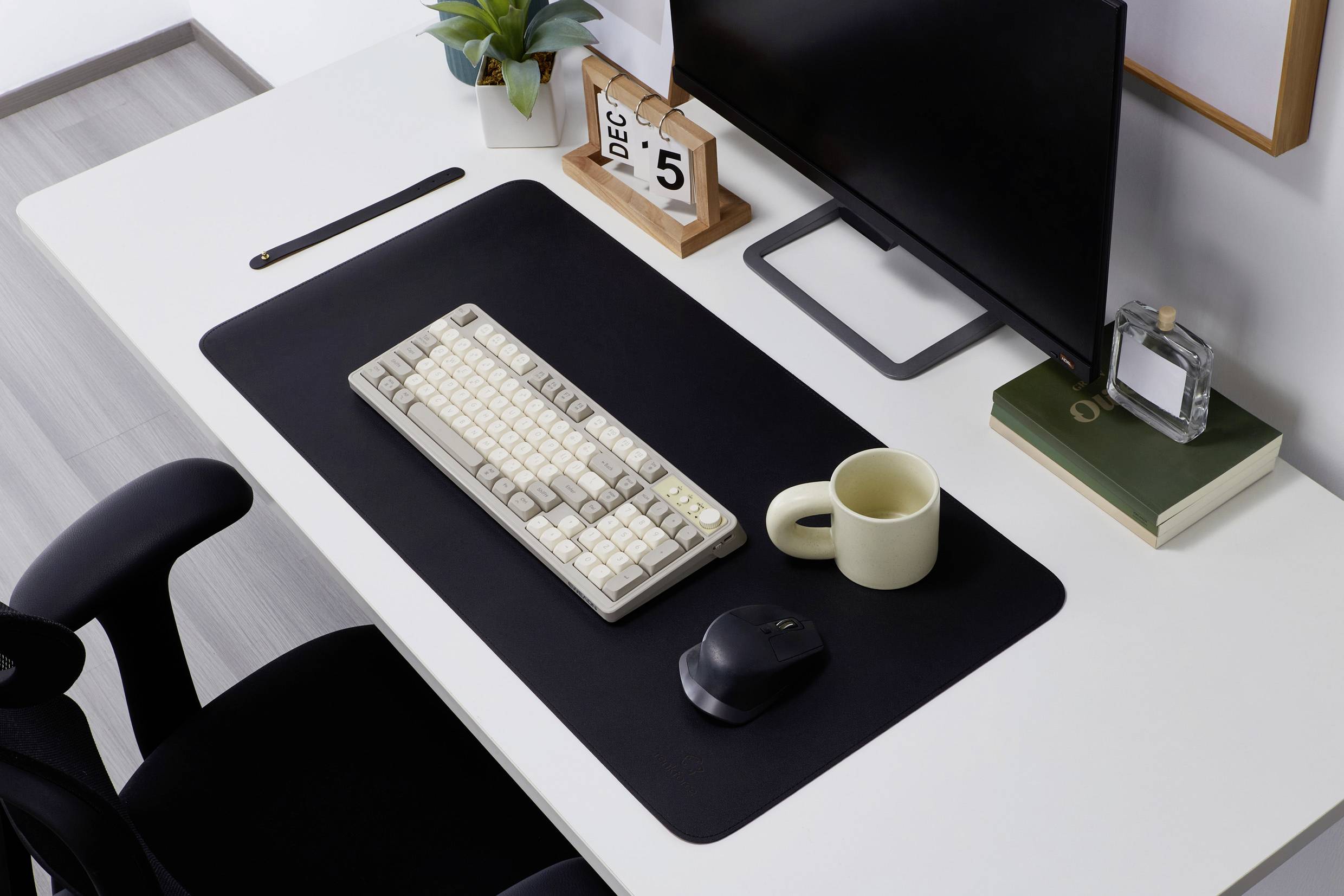 Ein aufgeräumter Schreibtisch mit Computer, Tastatur, Maus, Tasse und Dekorationen. Datum auf Kalender: 5. Dezember.